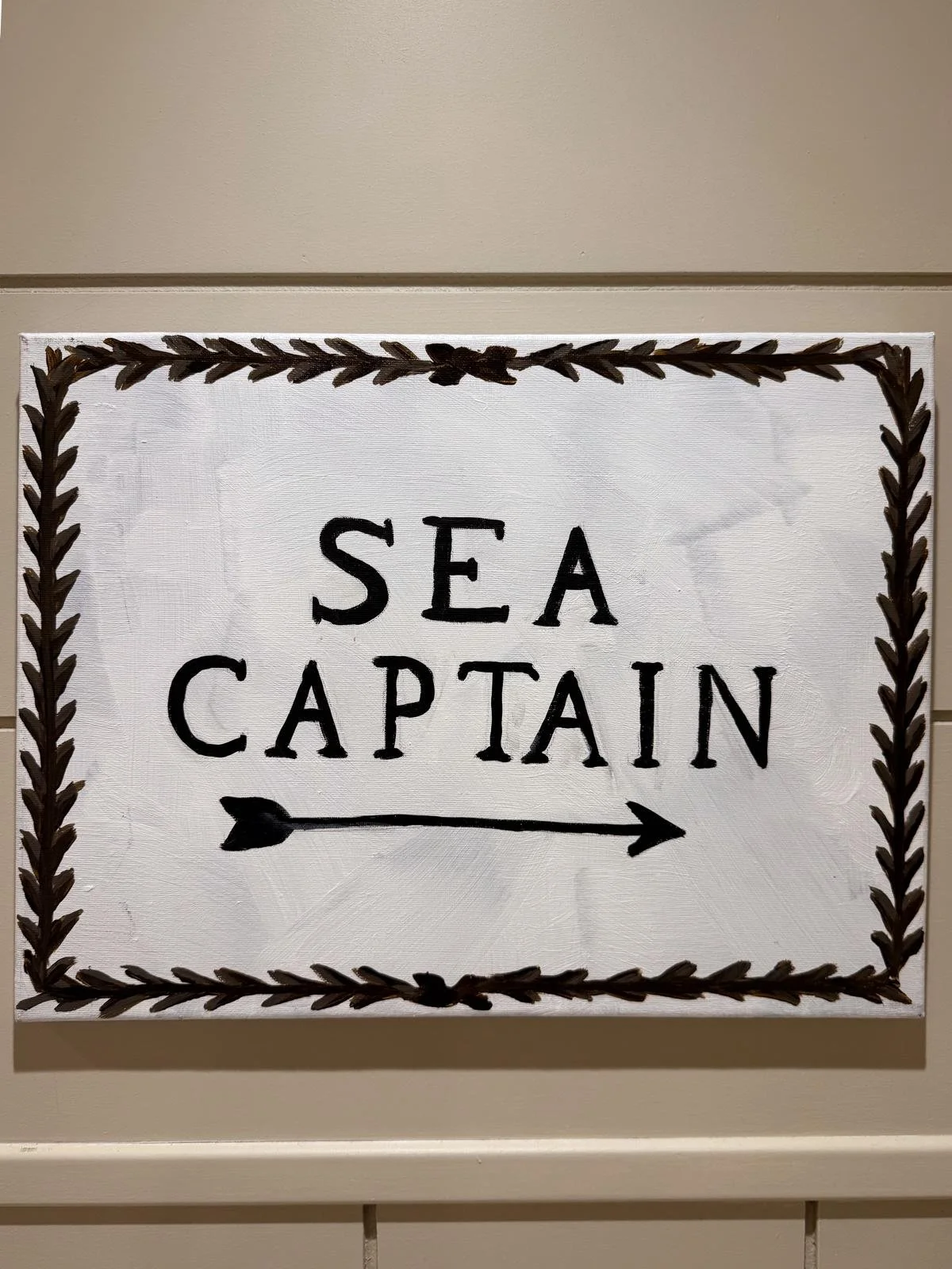 Hand-painted sign that reads 'Sea Captain' with an arrow pointing to the right, surrounded by a decorative rope border.