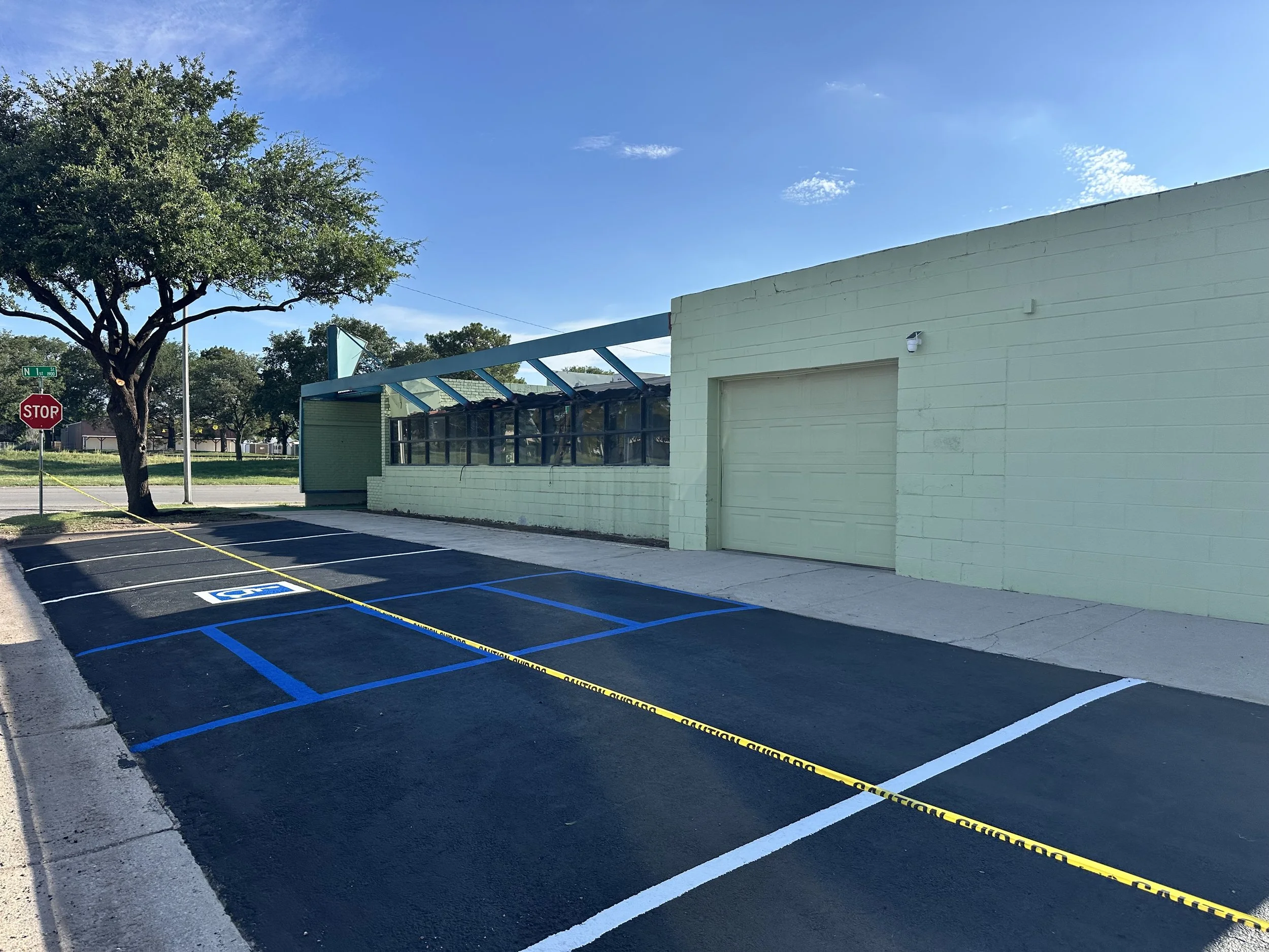Empty parking lot with white painted lines and a streetlamp near the center.