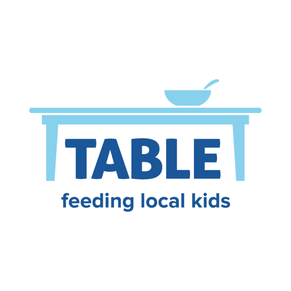 An illustration of a table with a bowl and spoon on top, with the words 'TABLE feeding local kids' underneath.