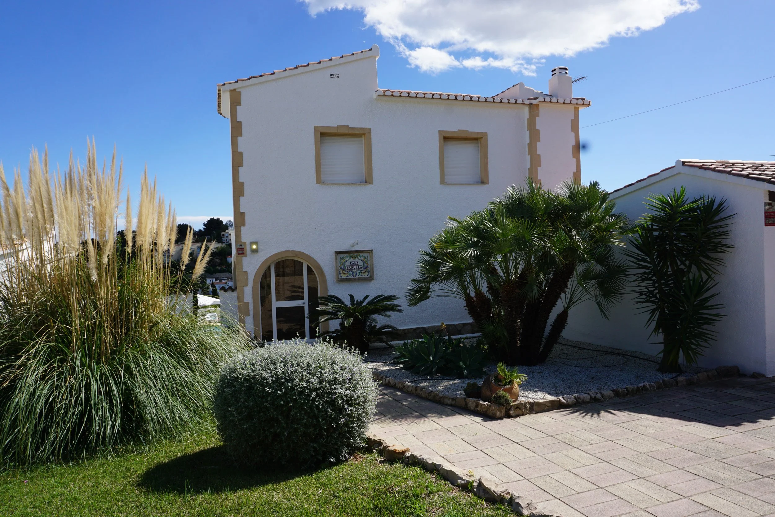 Voor aanzicht huis met tropische tuin met palmen, citroen-, sinaasappel- en mispelbomen en laurierstruiken