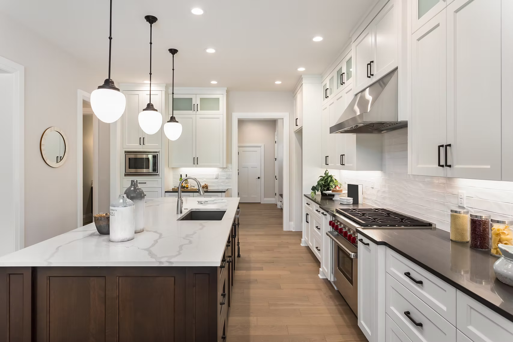 Modern kitchen with white cabinets, a wooden island, pendant lights, and stainless steel appliances.