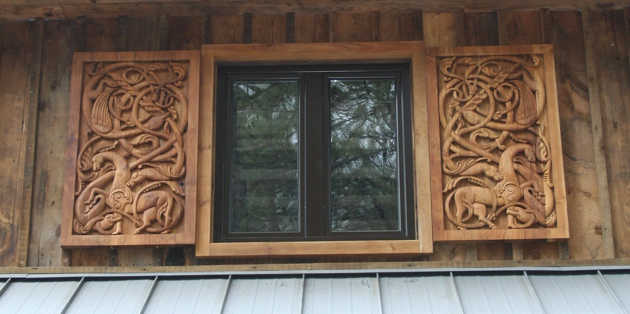 A window set in a wooden wall, with intricate wood carvings of intertwined dragons on both sides of the window.