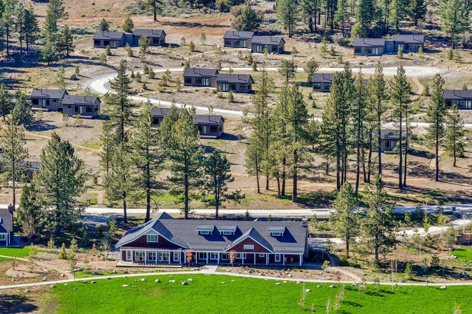 Aerial view of a ranch-style lodge and private cabins situated among pine trees and open meadows at a corporate retreat center.