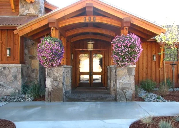 Wooden house entrance with stone pillars and hanging flower baskets