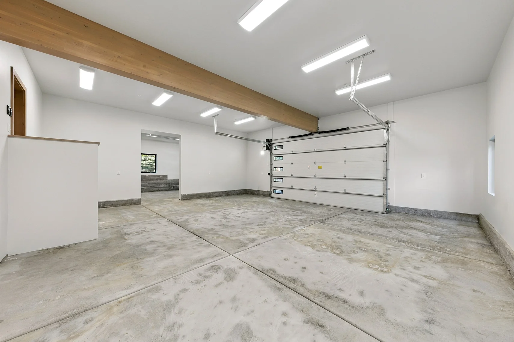 Modern three-car garage with two double-bay doors and a single-bay door separated by a wall with a large open entryway.