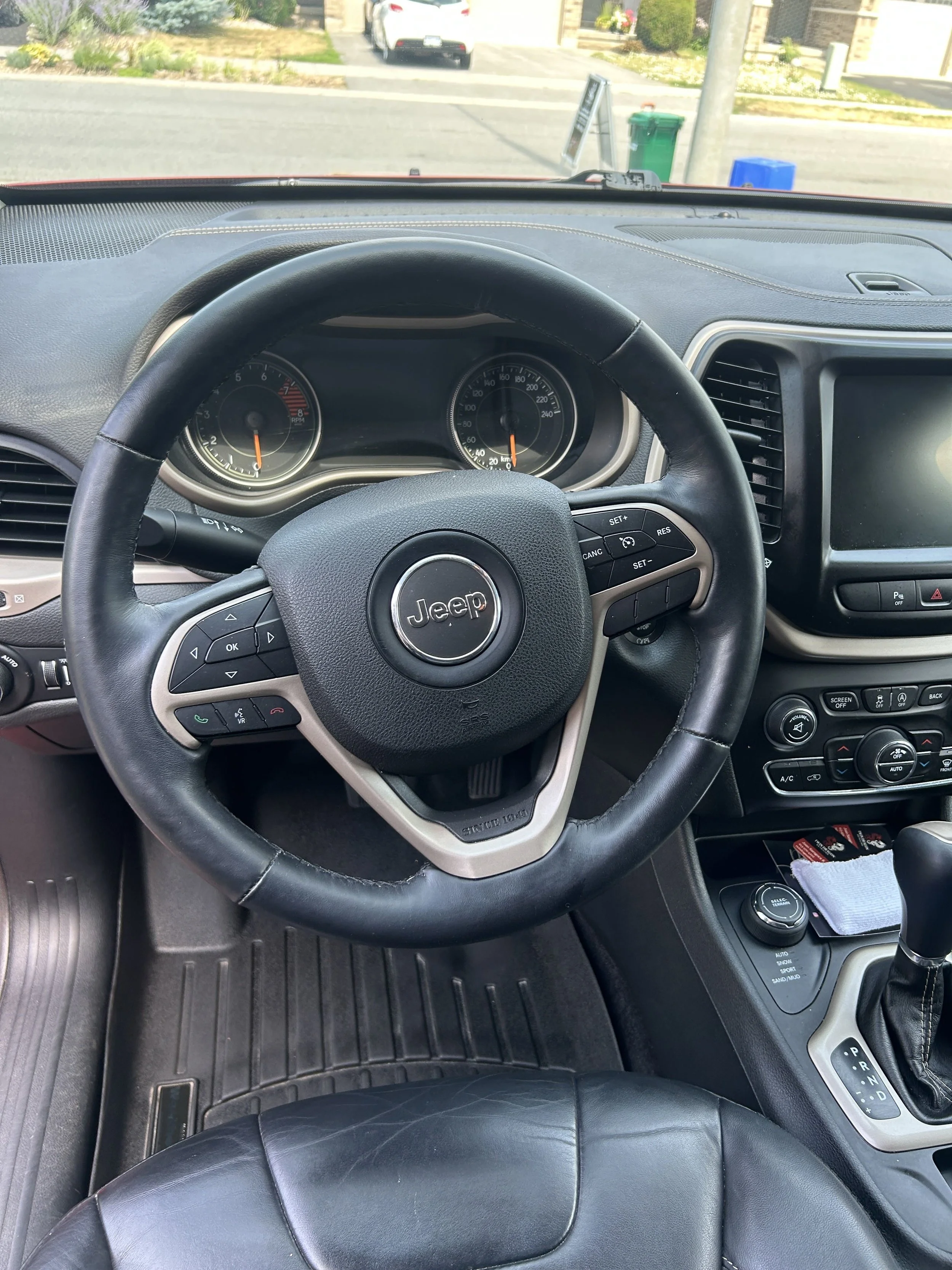 Interior view of a Jeep vehicle dashboard showing the steering wheel, instrument cluster, center console, and gear shift.