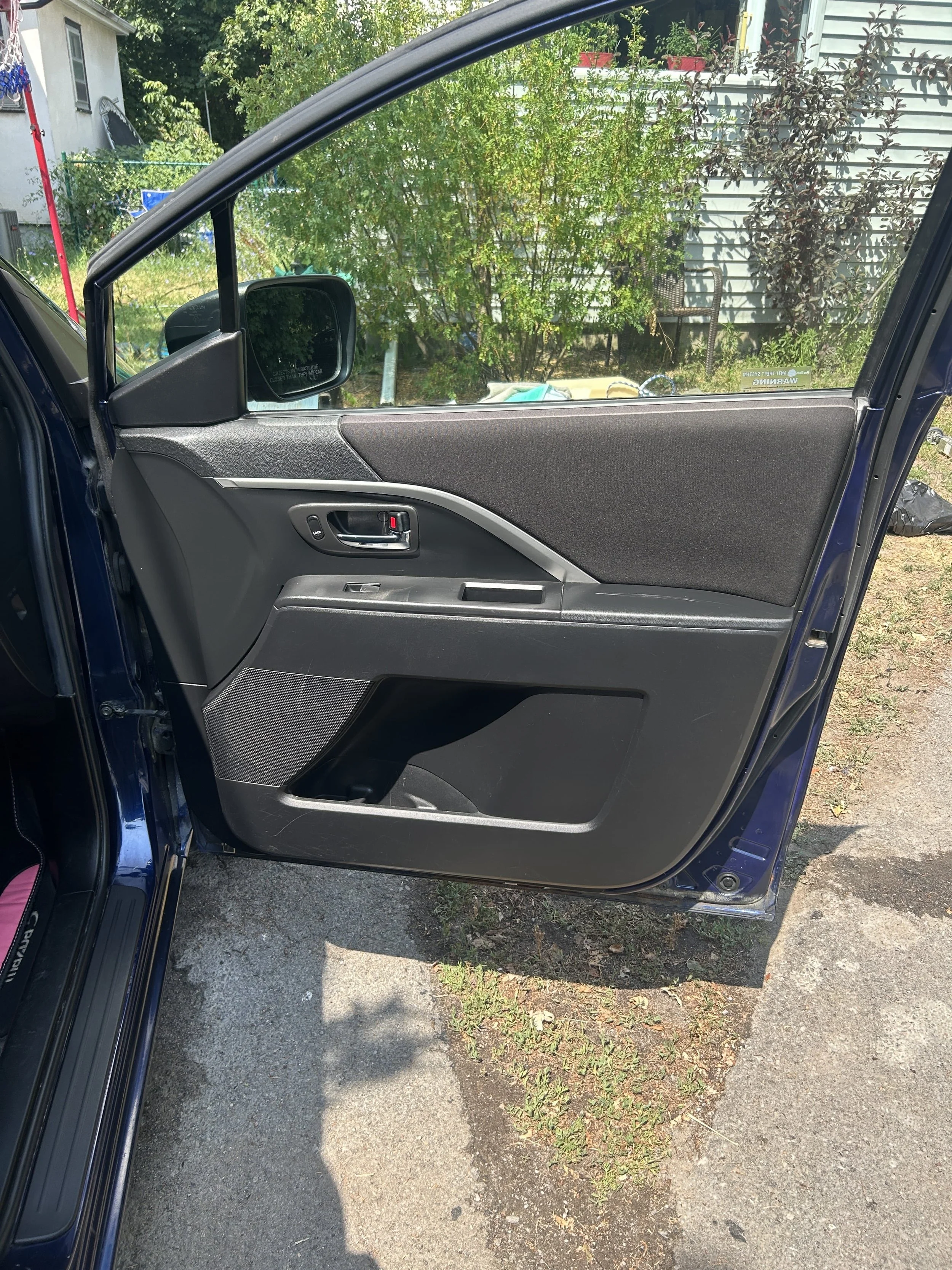 Front passenger side door of a car showing the interior panel, window, mirror, and handle.