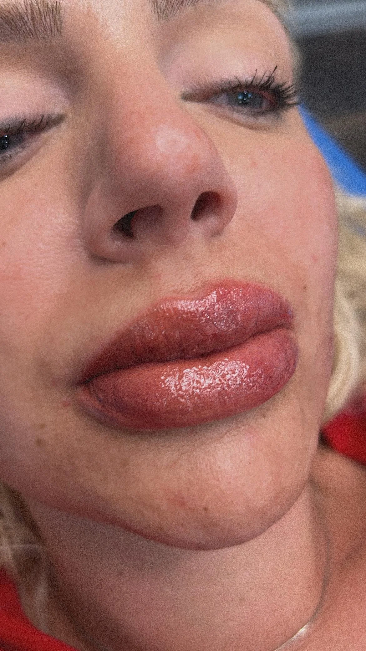 Close-up of a woman's face, focusing on her full, glossy lips and partially closed eyes with long eyelashes.