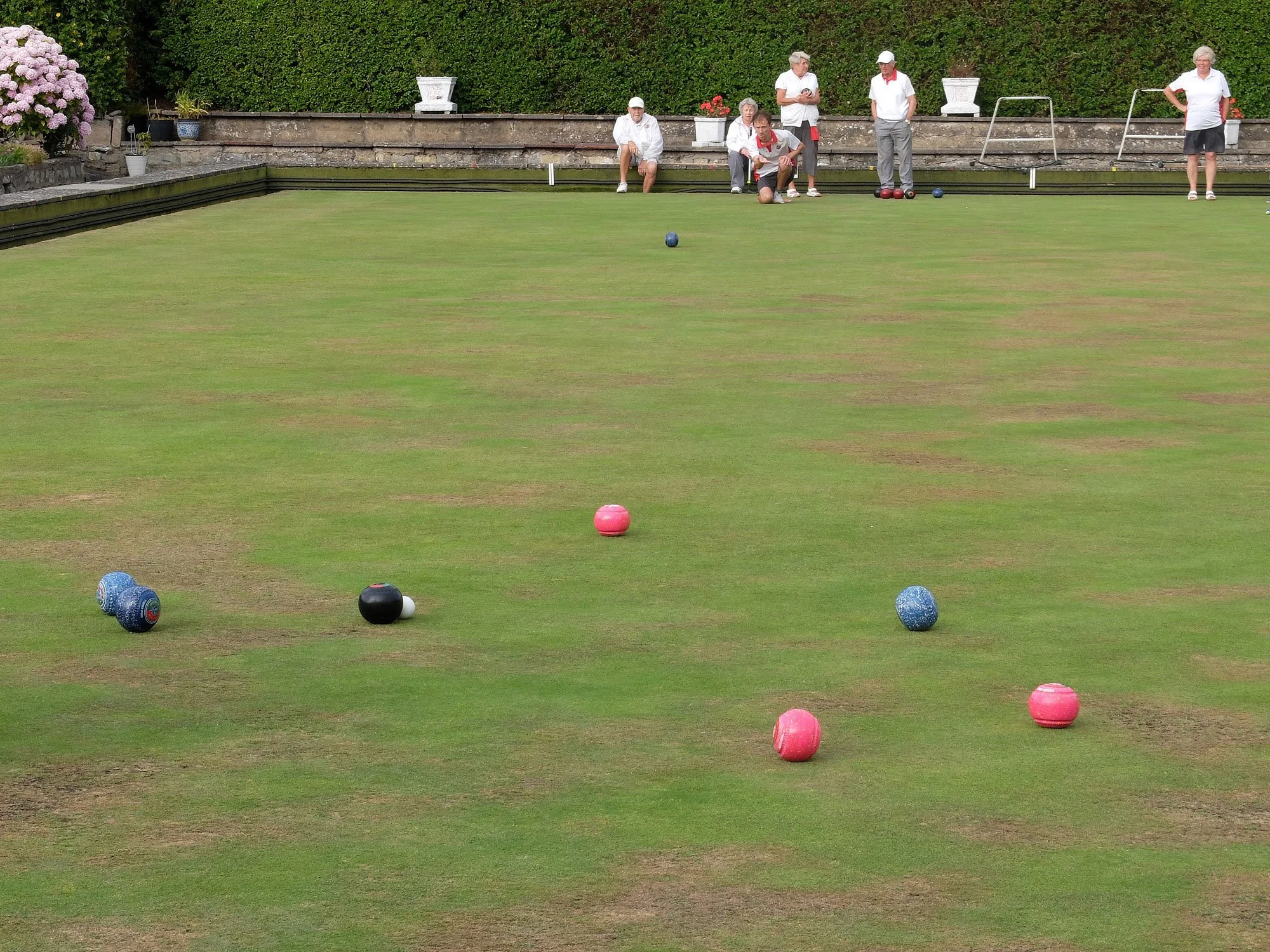 People playing lawn bowls on a green garden.