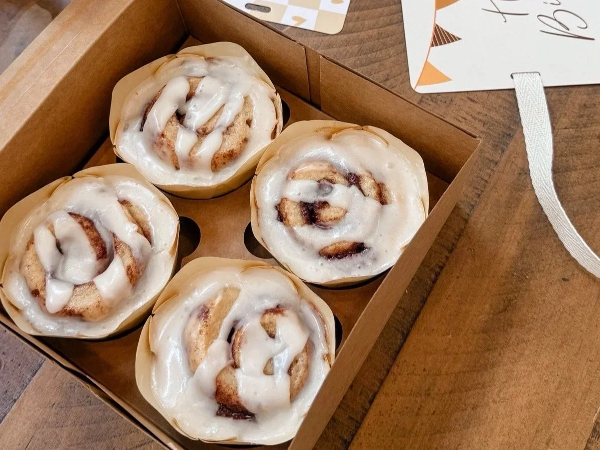 A box of four cinnamon rolls with vanilla icing.