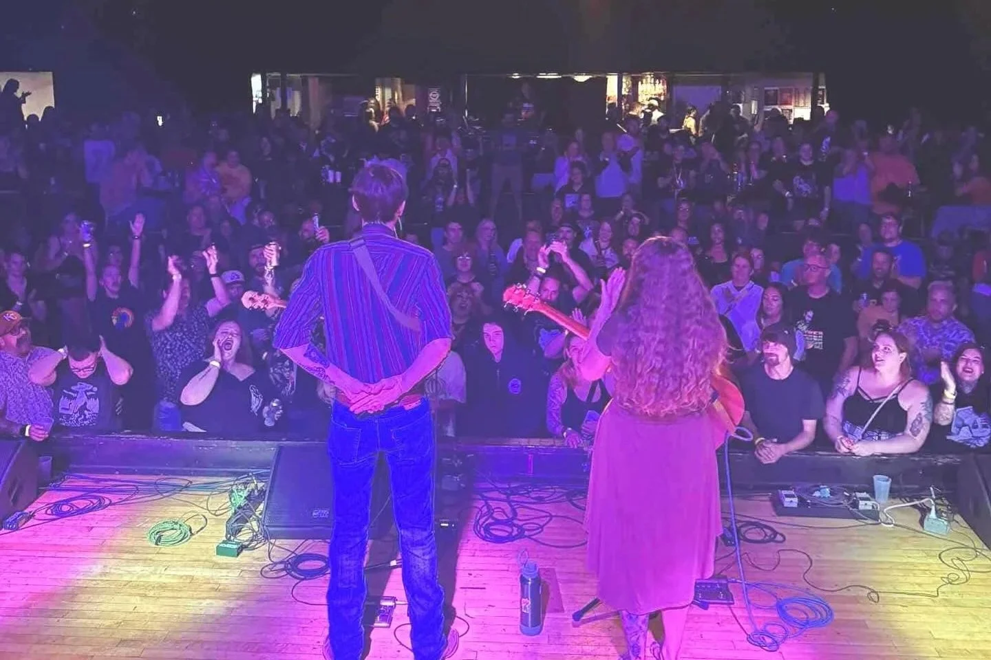 Photo of Rachel & Griffin on stage in front of a crowd of people at The Granada Theater in Lawrence, KS.