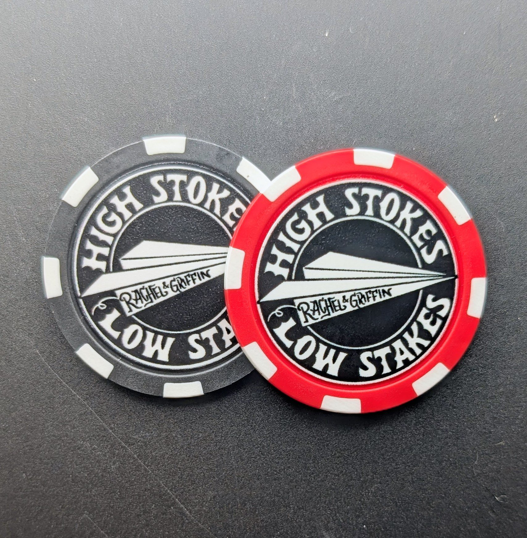 a red and a black poker chip with high stokes, low stakes design featuring paper airplane