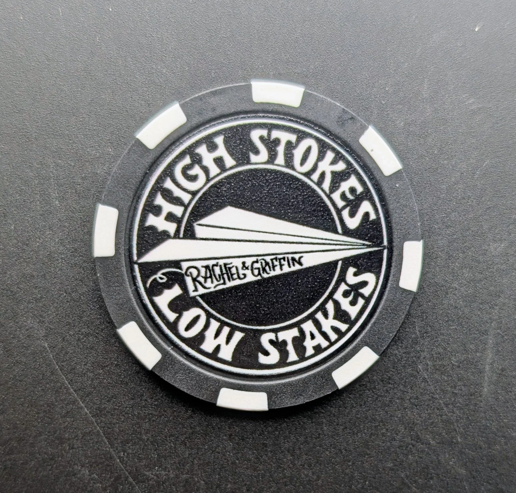 black poker chip with paper airplane design
