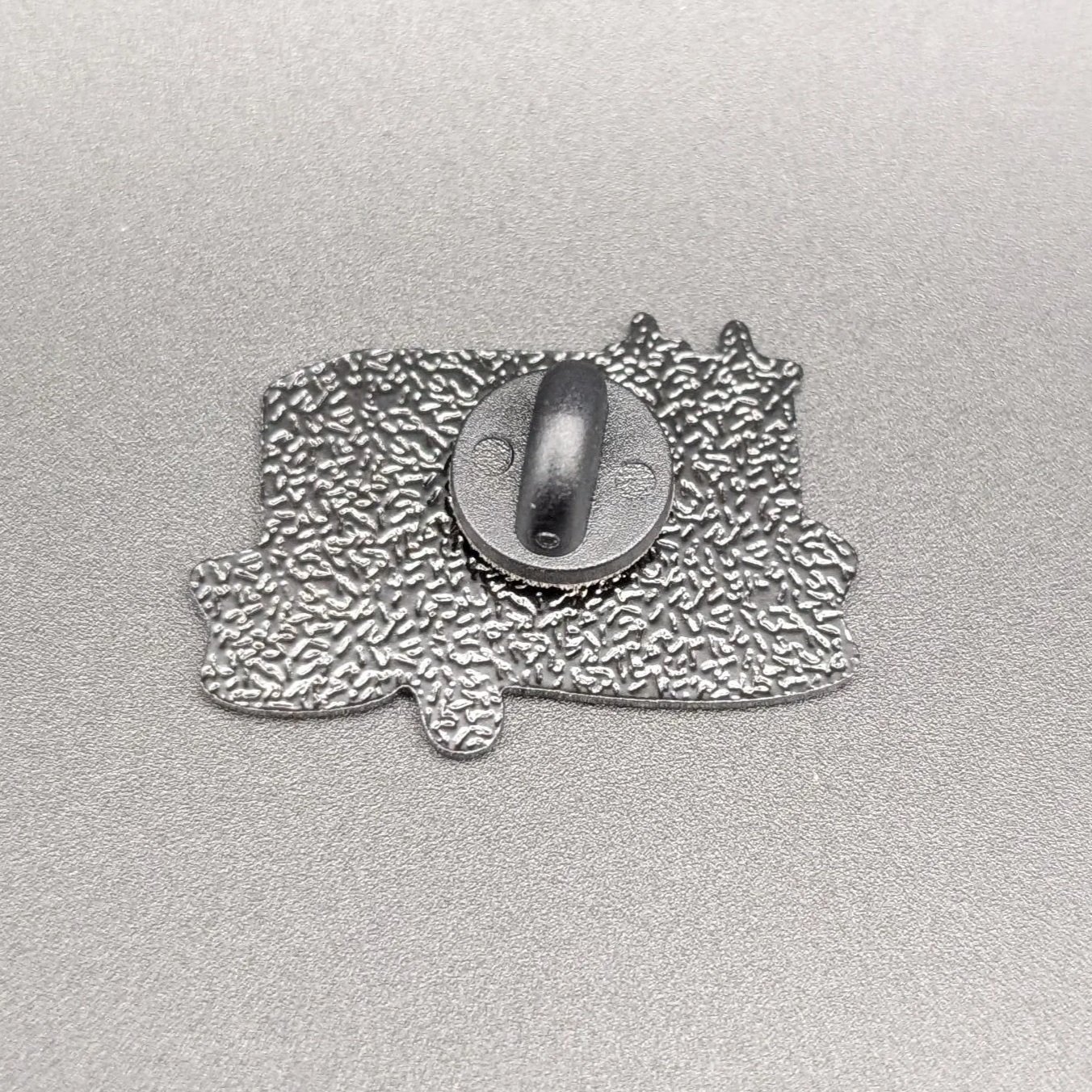 Back of the Make Me Melt soft enamel pin with metal post and black rubber backing
