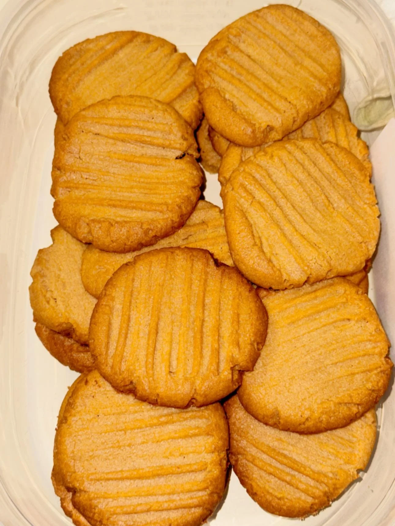 A container of crispy, golden brown peanut butter cookies with ridges.