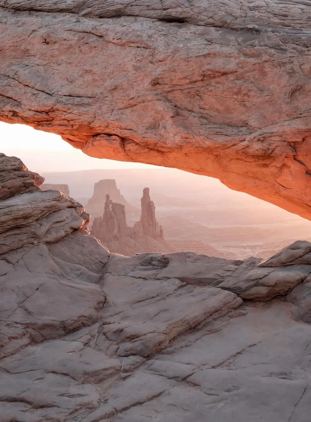 View through the gap of a red-tone rock formation into other rock formations in the distance.