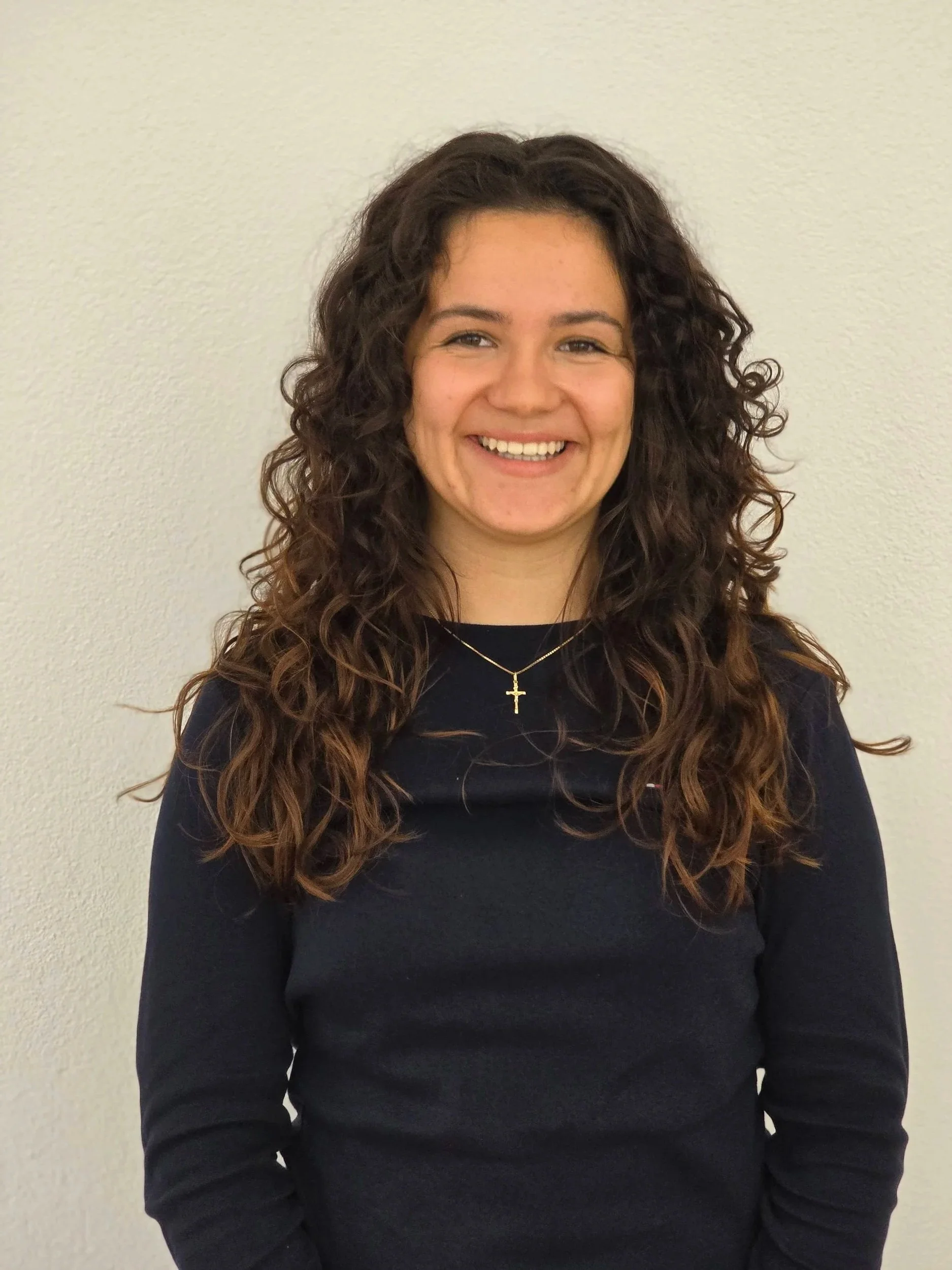 Sofia mit dunklen Locken im dunklen Oberteil, lächelt