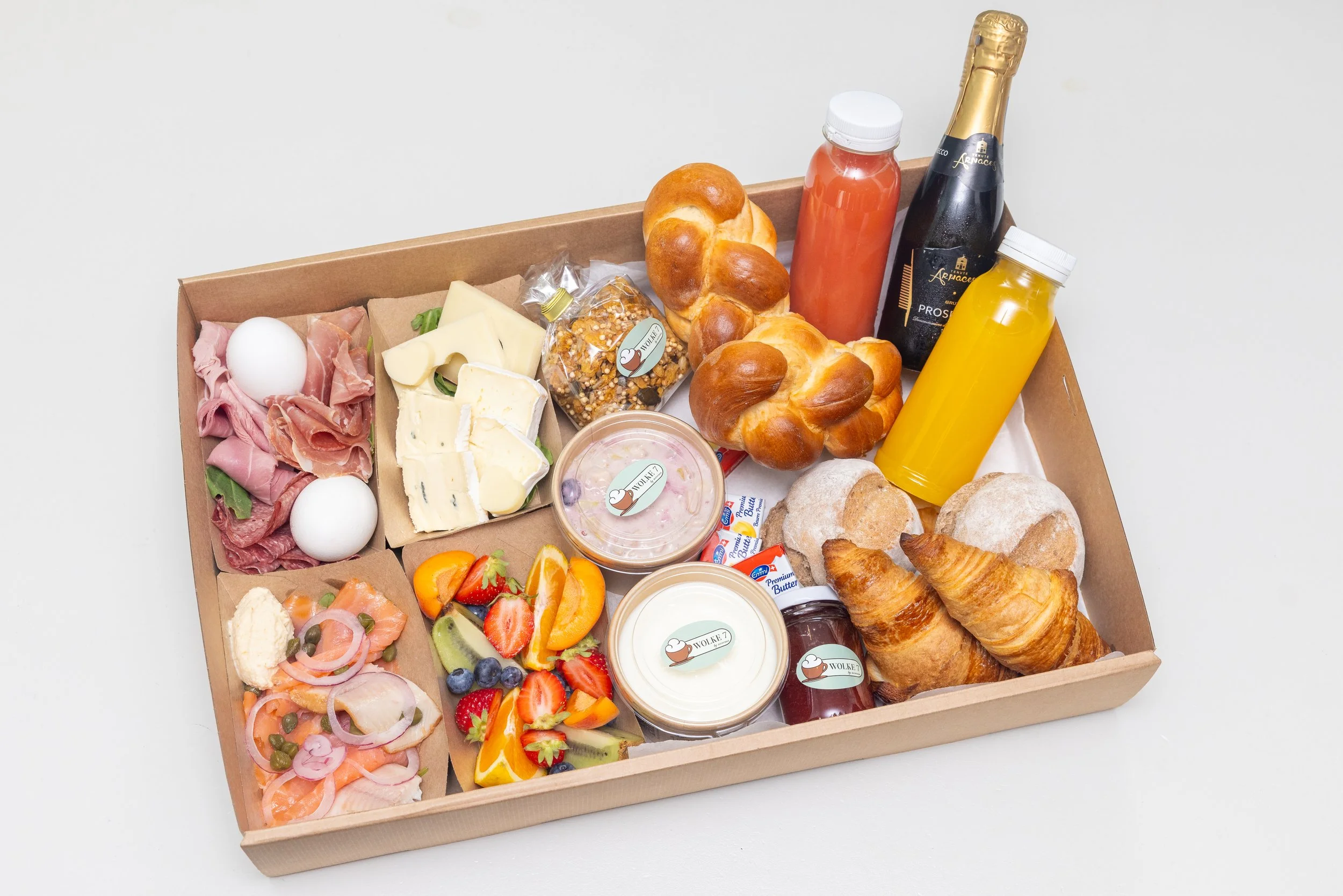 Brunchbox mit Gipfeli, Orangensaft, Aufschnitt, Käse, Früchten und Aufstrichen