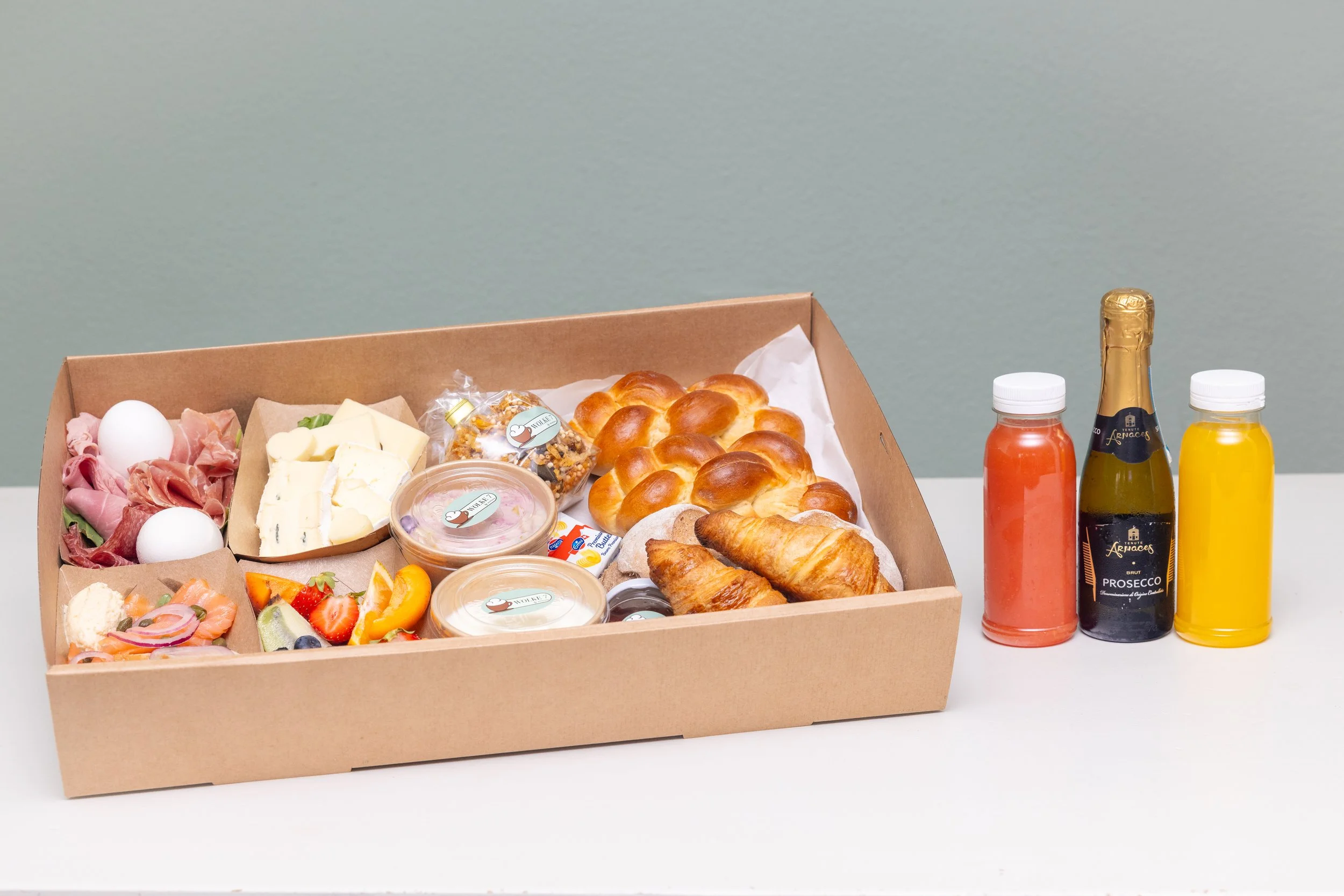 Brunchbox mit Gipfeli, Orangensaft, Aufschnitt, Käse, Früchten und Aufstrichen