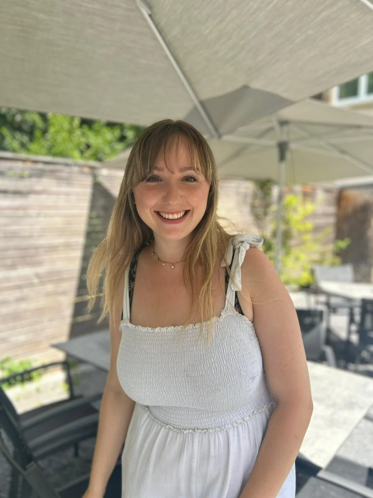 Remi im weissen Oberteil im Garten, strahlend