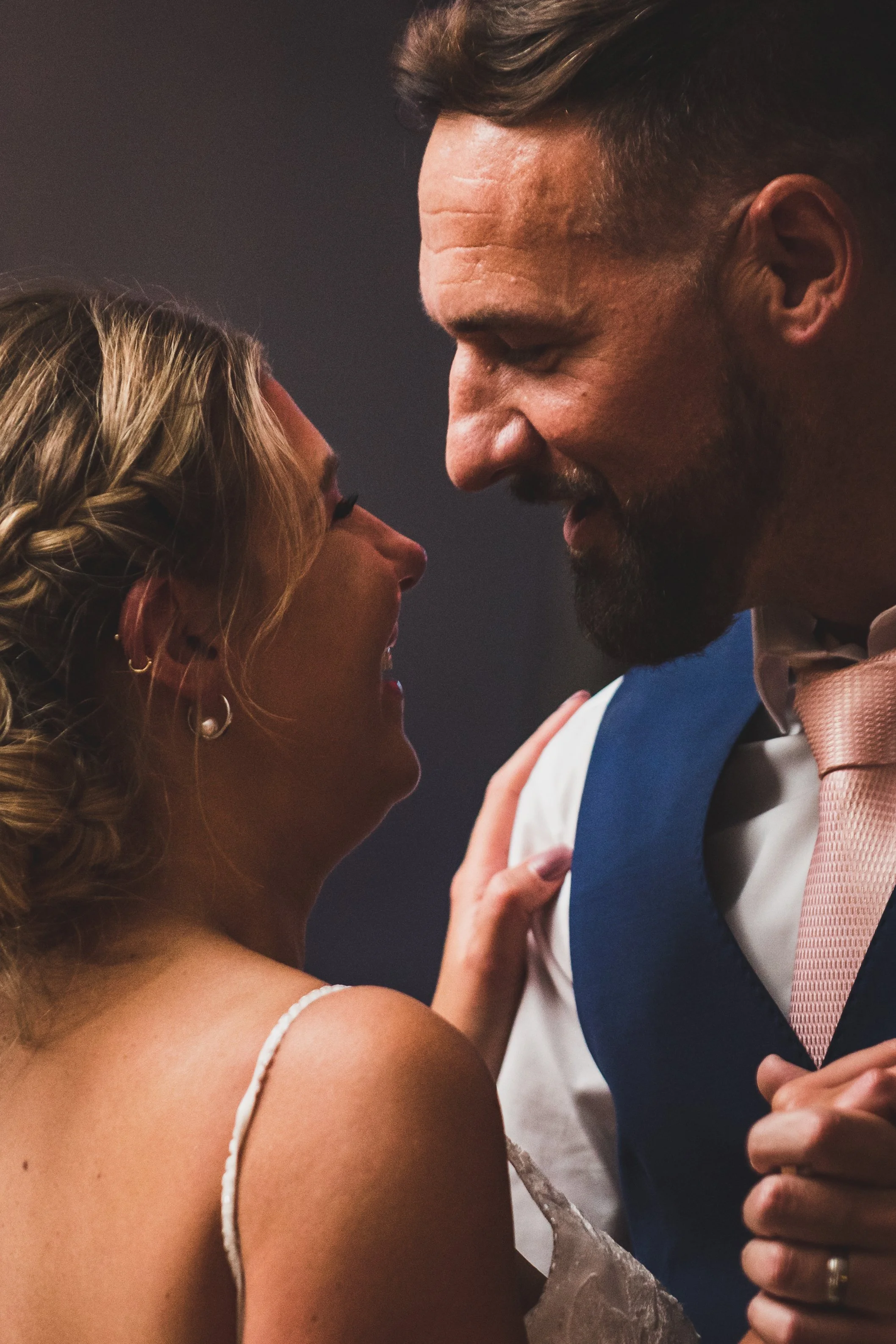A couple sharing a romantic moment, close-up, with their foreheads and noses touching, smiling at each other.