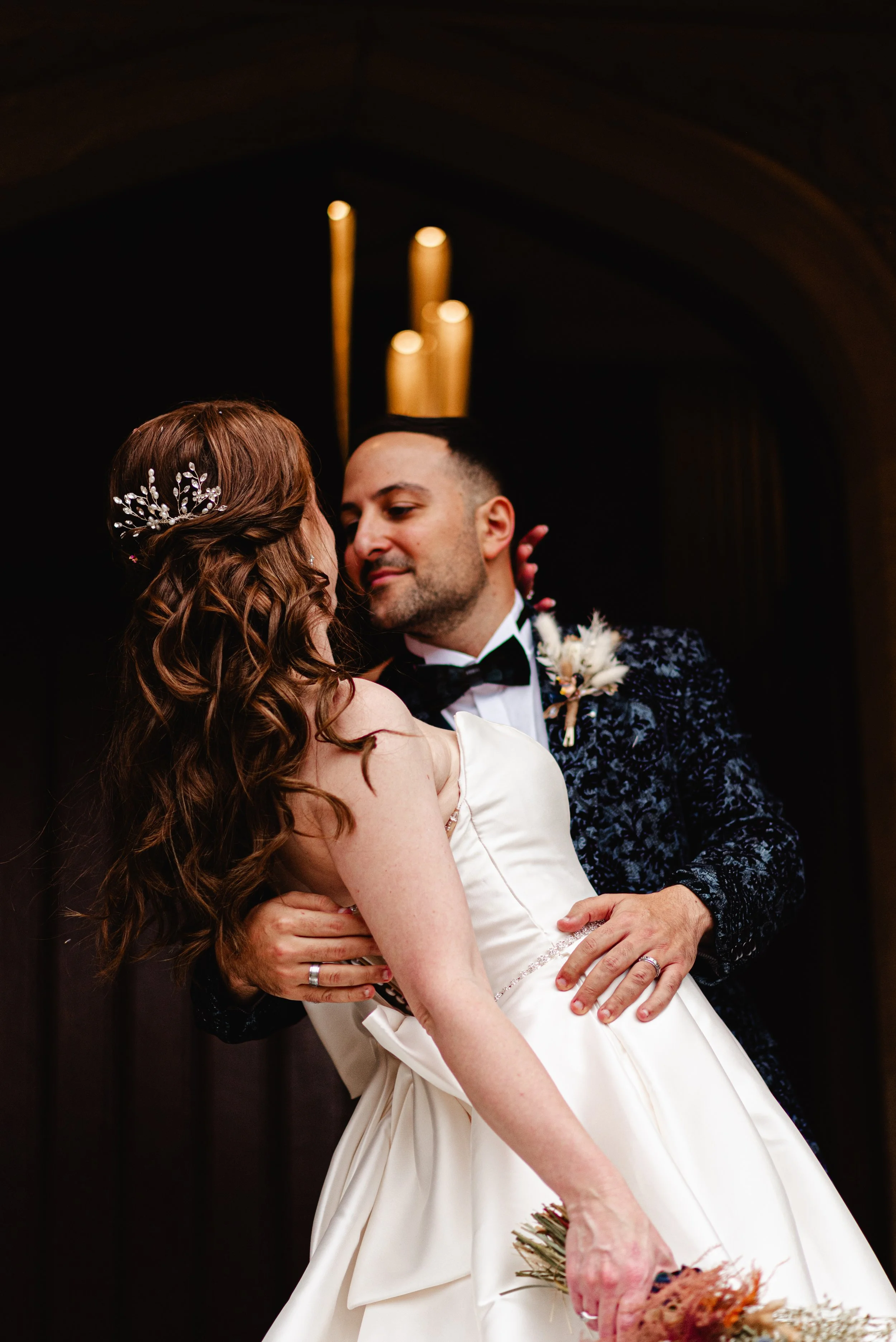 A groom and bride sharing a dance at a wedding, with dim lighting and modern decor in the background.