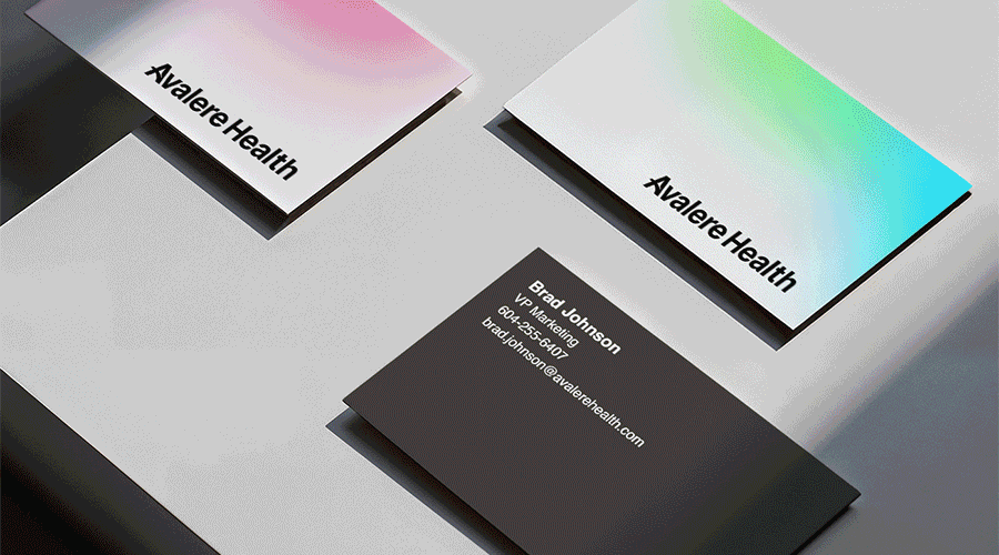 Three business cards for Avalere Health on a white surface, one black with white text, two with gradient backgrounds, one pink and white, the other green and blue.