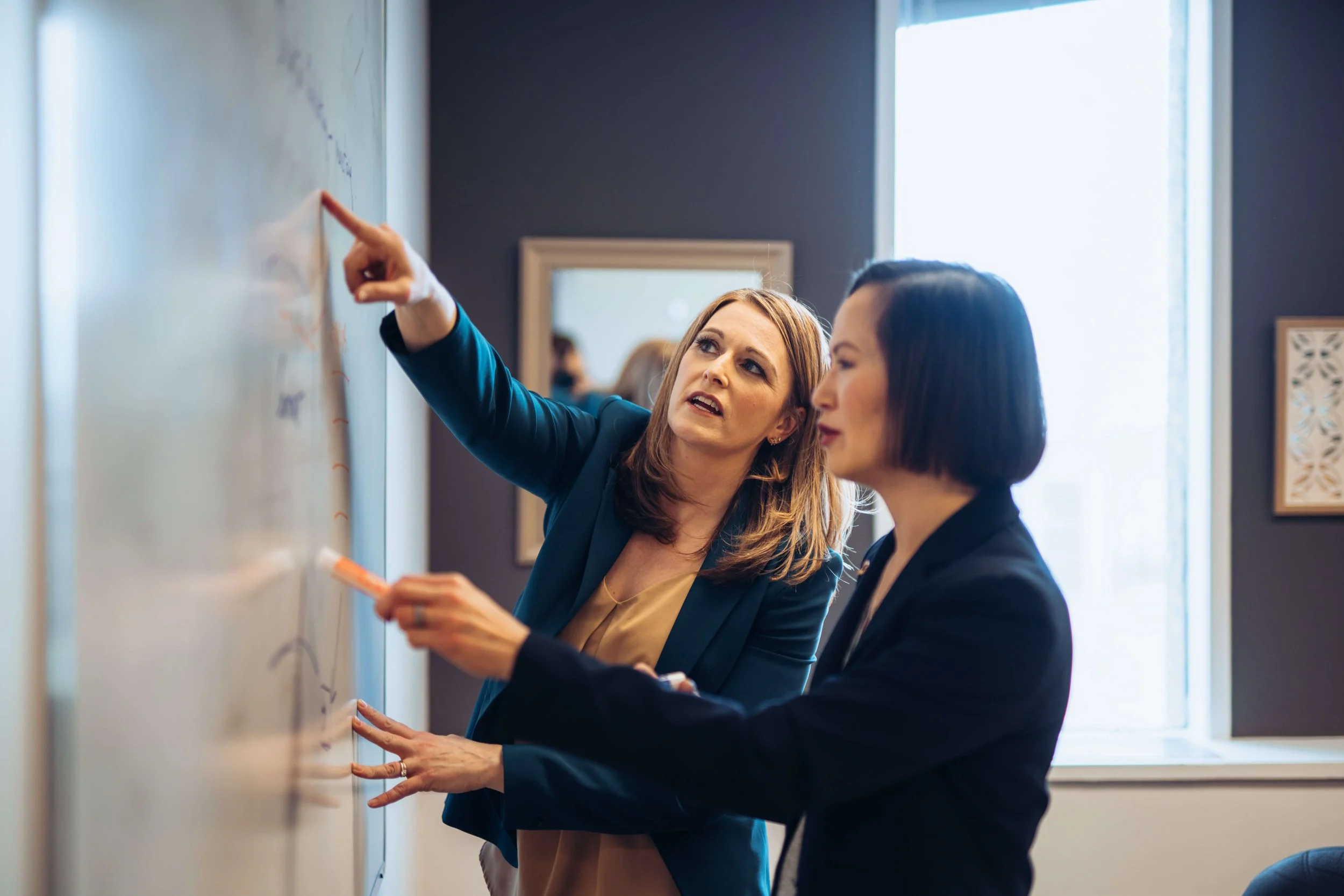 Separation and divorce coach in Saskatoon, Lana Wickstrom, is discussing something at a whiteboard with a client.