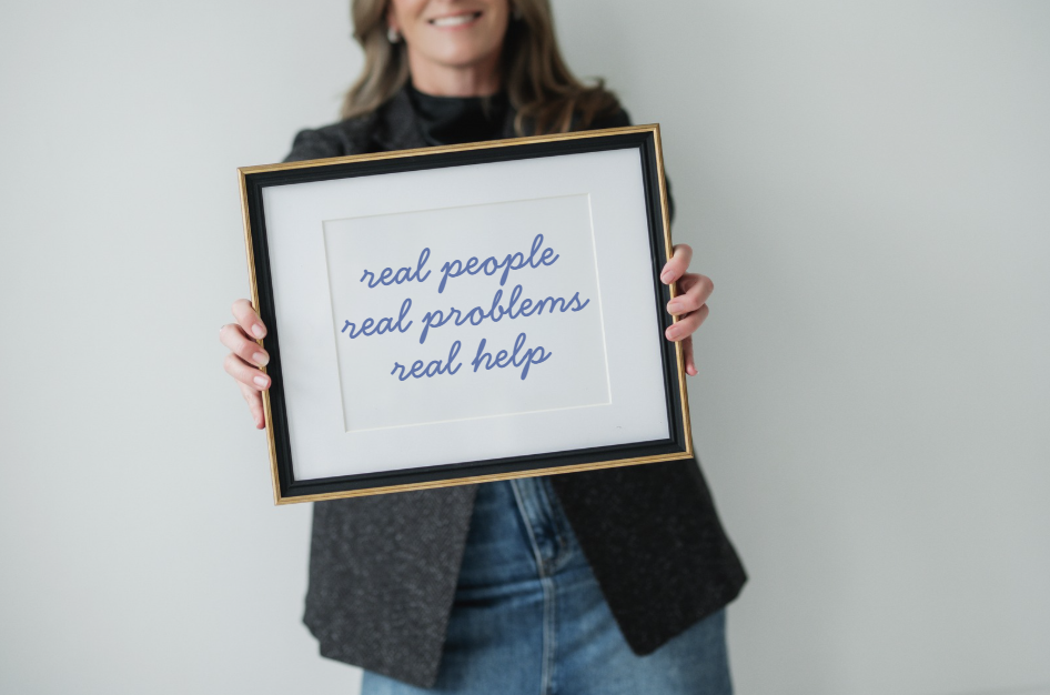 Separation and divorce coach Lana Wickstrom in Saskatoon is holding a framed sign that says 'real people real problems real help'