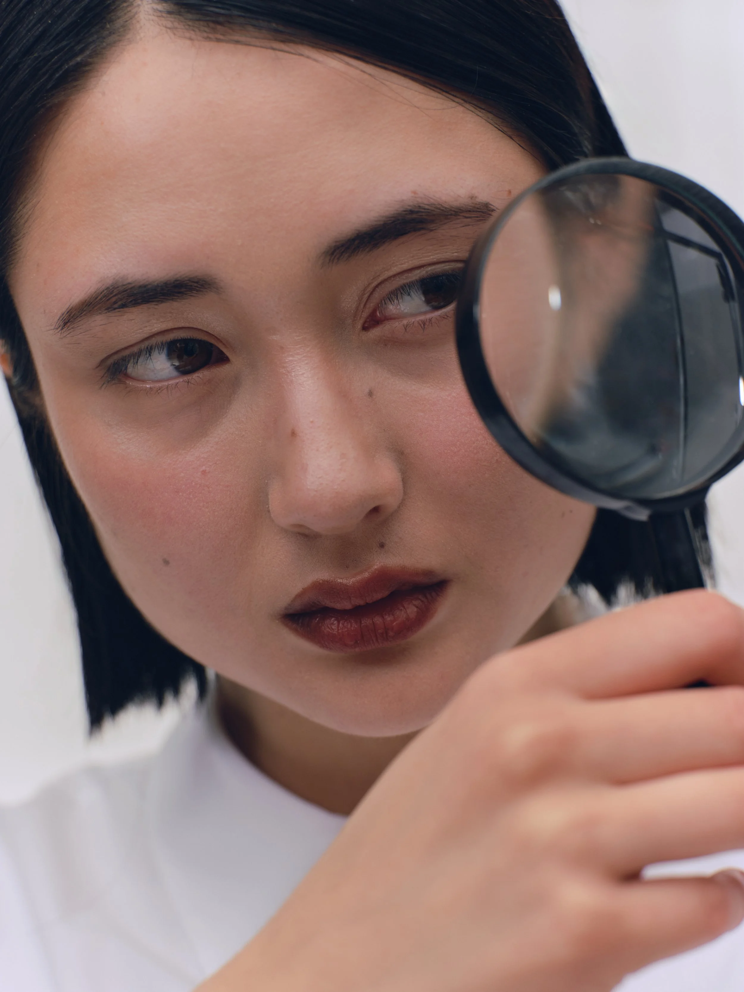 A woman examining something with a magnifying glass.