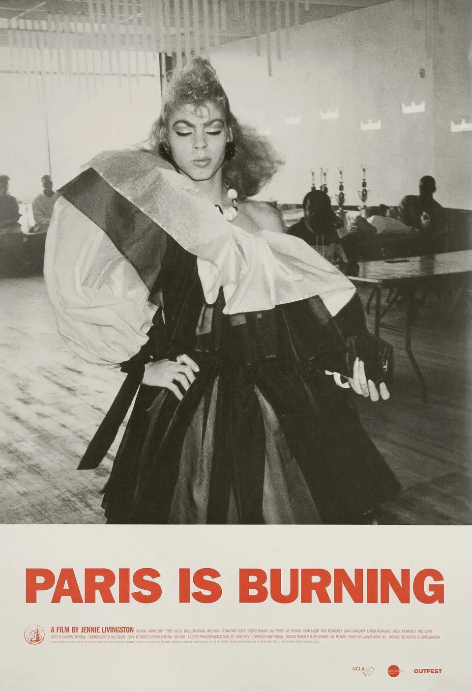 Black and white promotional poster for the film 'Paris Is Burning', featuring a woman with voluminous curly hair in 1980s fashion, standing with her hand on her hip, with a background of seated silhouettes.