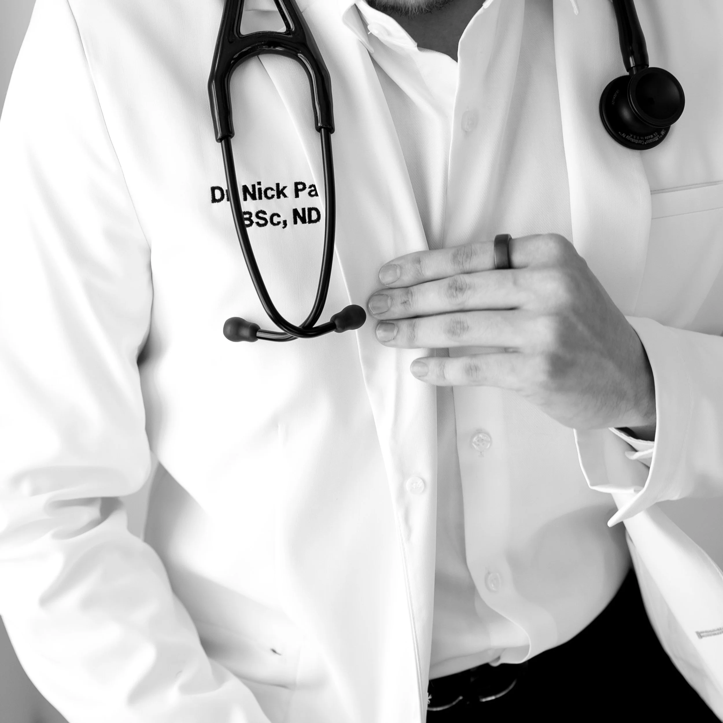 Close-up of a medical doctor in a white coat with a stethoscope around his neck, putting his hand over his chest.