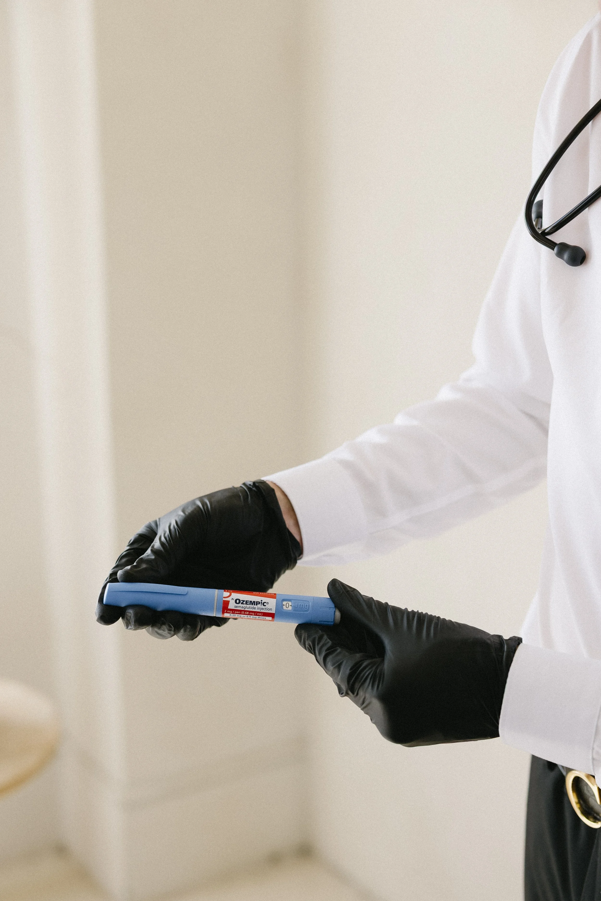 Medical professional in gloves holding a blue syringe with medication in a clinical setting.