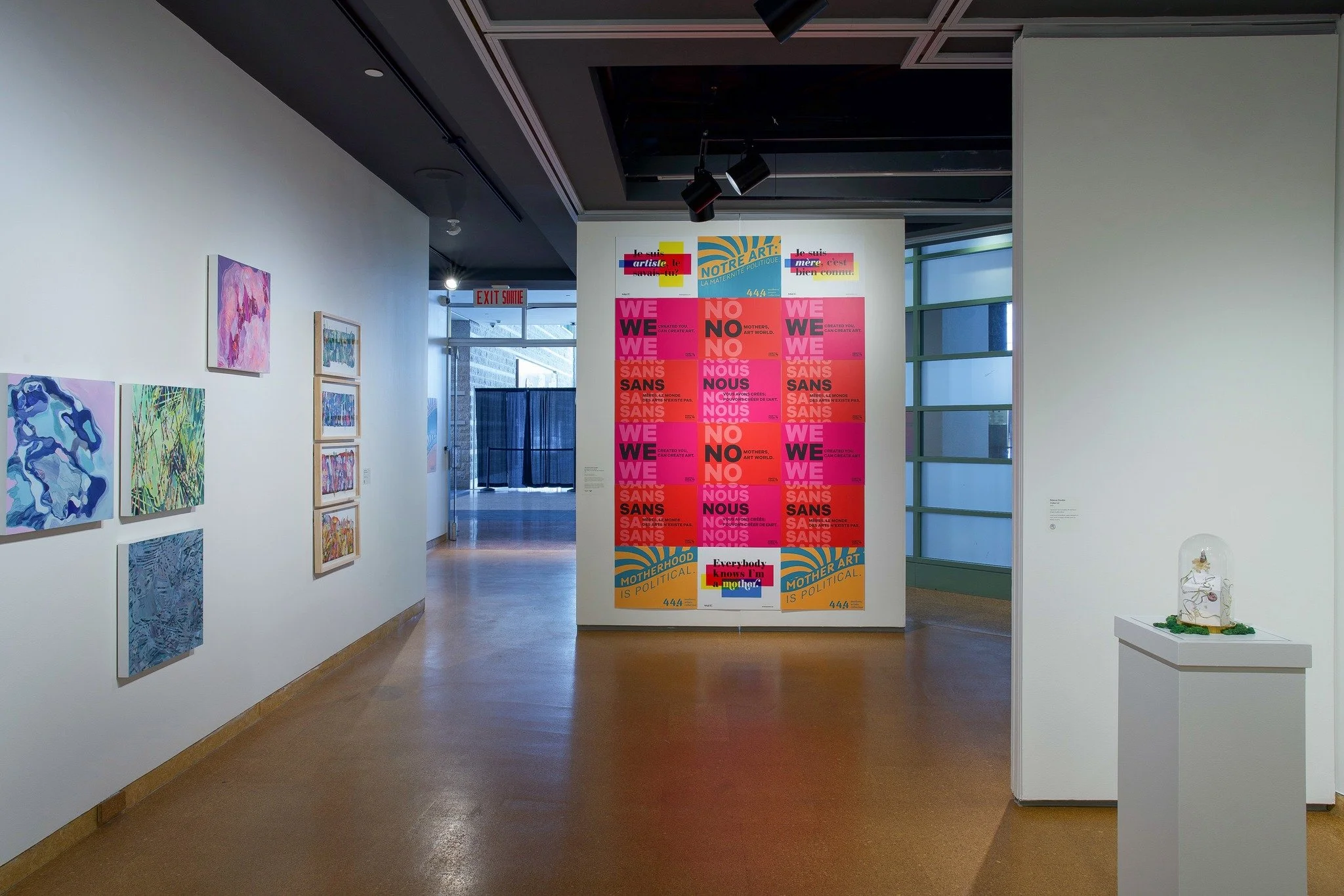 An art exhibition with a wall of colourful mother artist campaign posters 