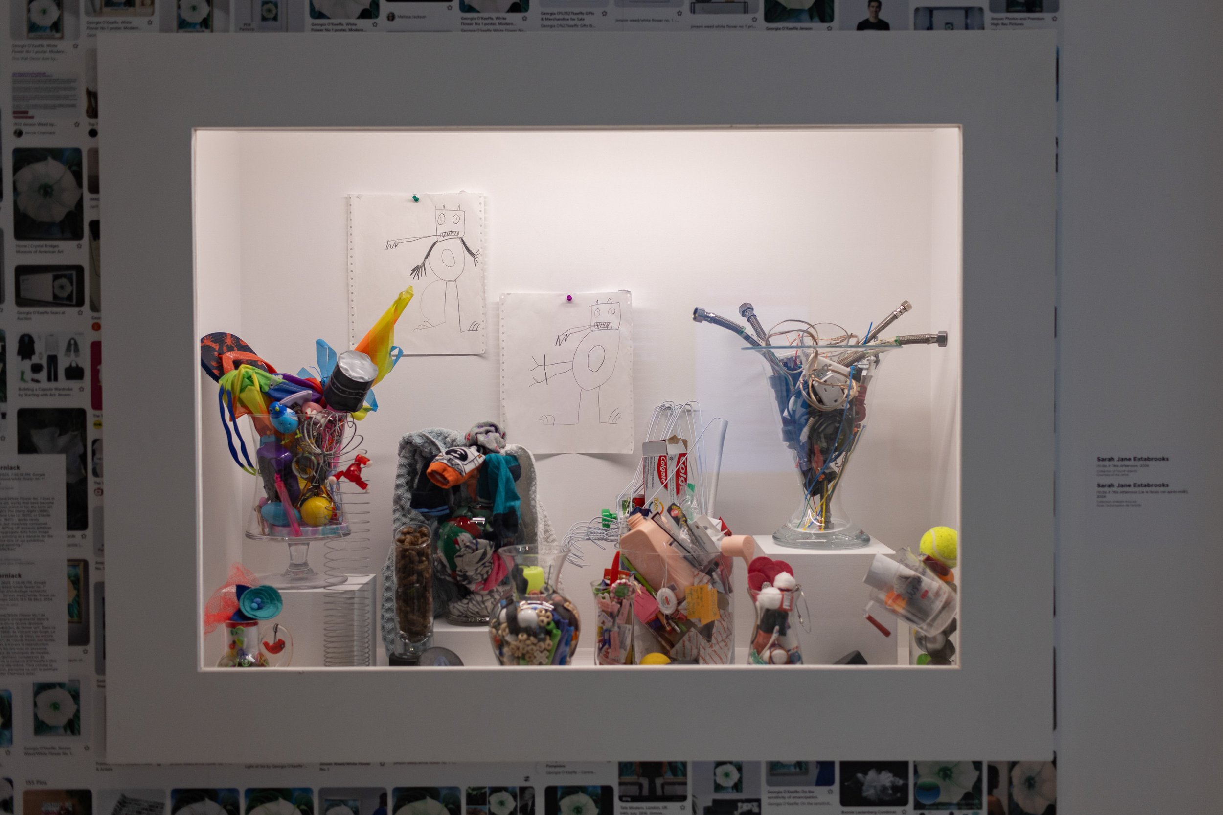 Artworks by Sarah Jane Estabrooks sit in a vitrine. Glass containers full of colourful objects