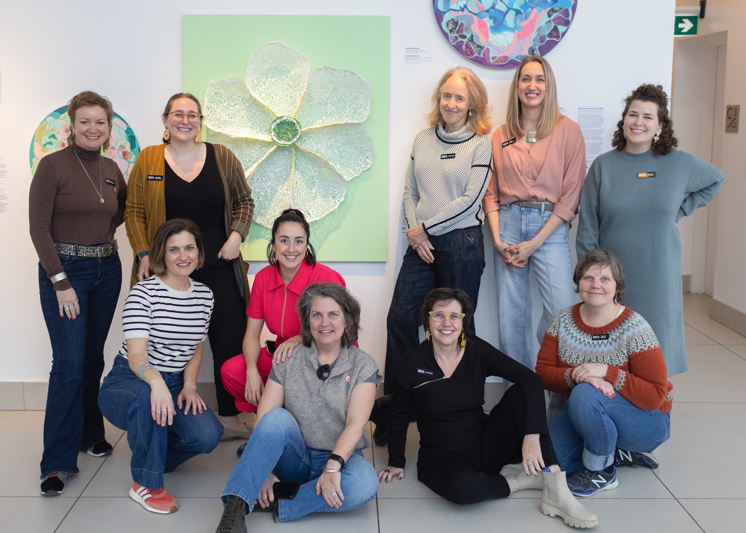 Members of the 44.4 Collective stand and sit in front of their art at the Ottawa Art Gallery