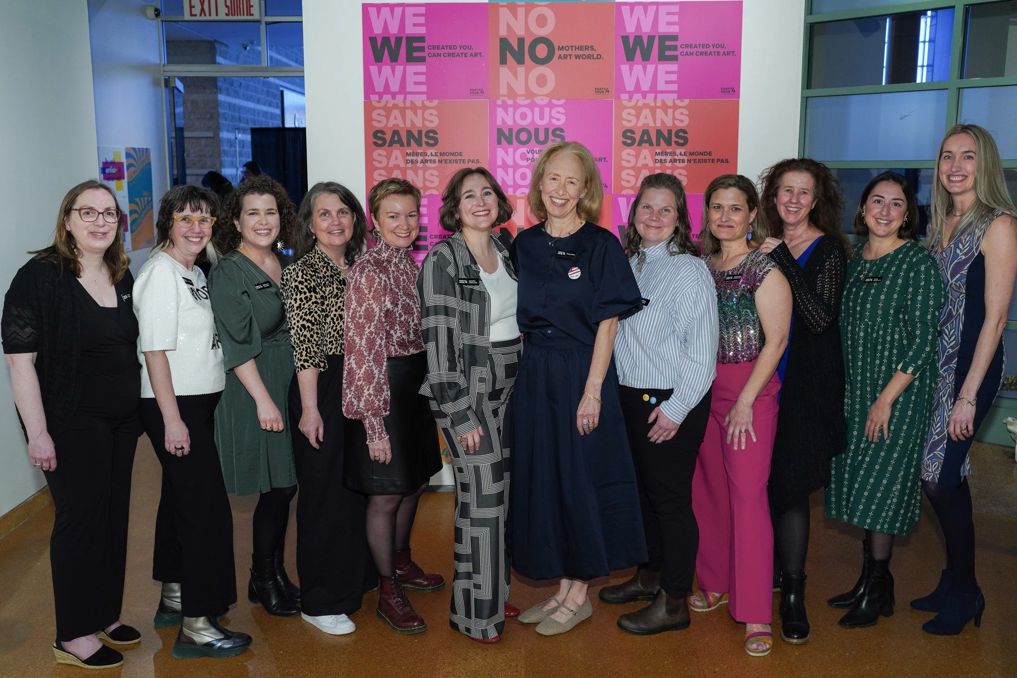 44.4 collective members stand in front of the Mother Artists Campaign posters