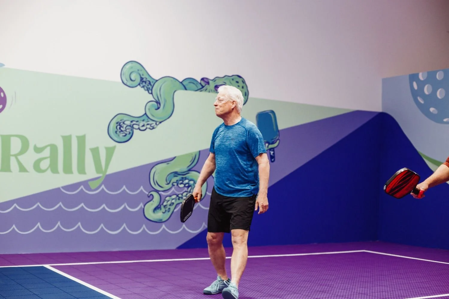 man with grey hair playing pickleball in a fun creative pickleball facility in Nova Scotia