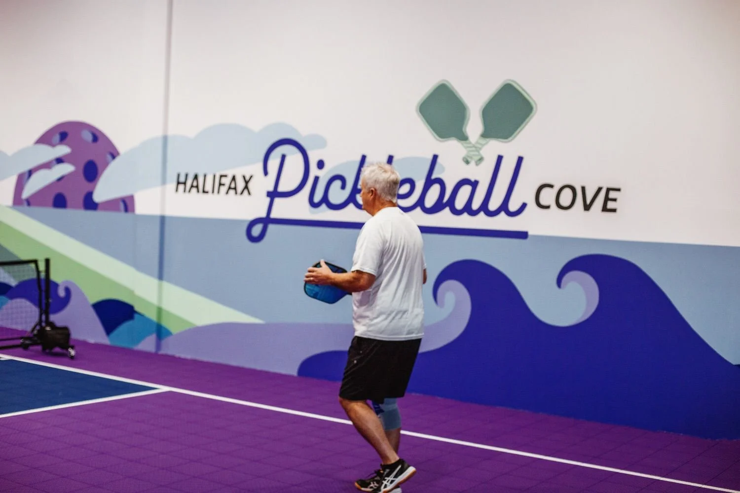 A man holding pickleball paddle at pickleball cove