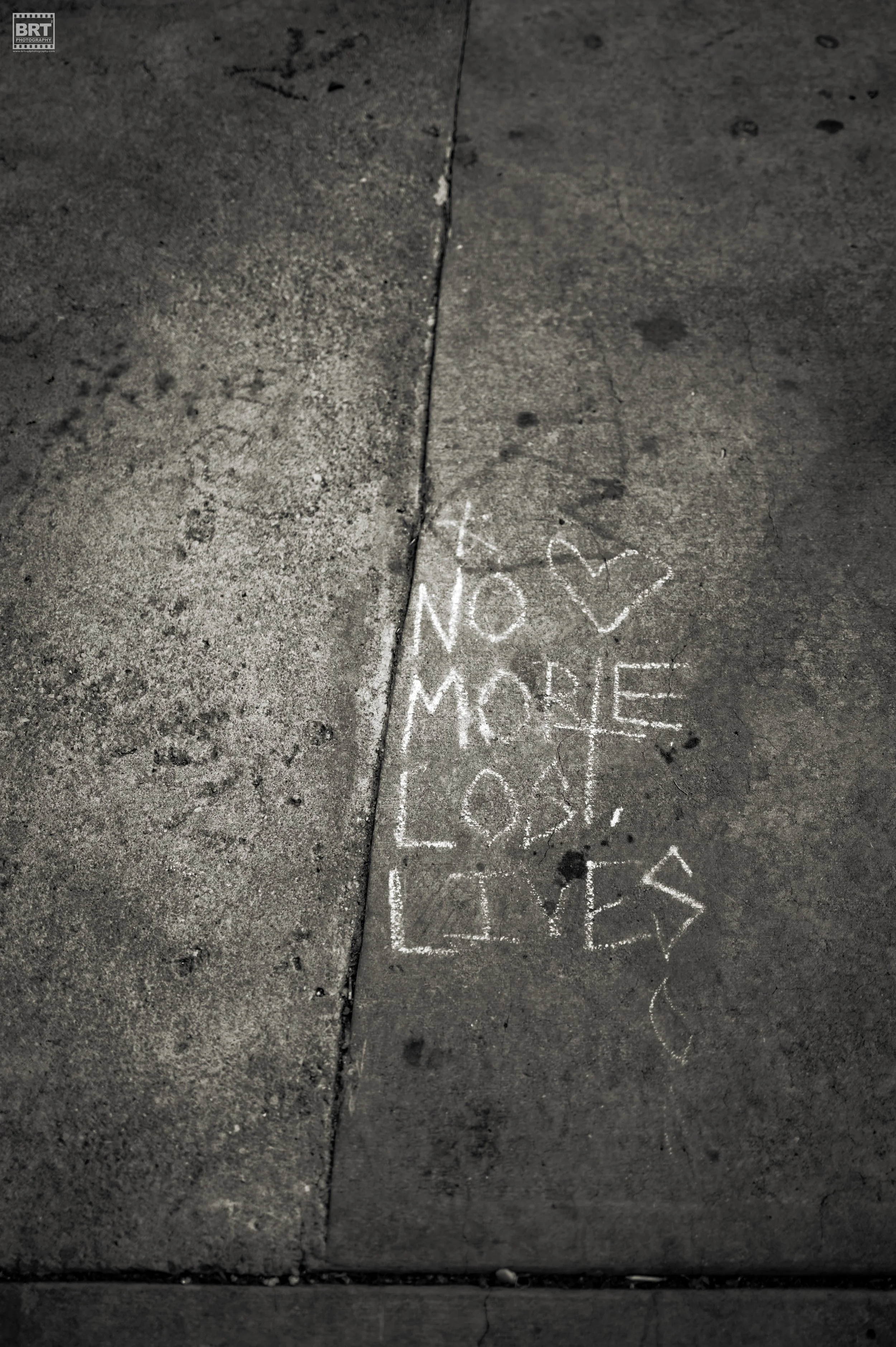 Chalk writing on sidewalk that says 'No More Lost Loves' with a heart shape above the words.