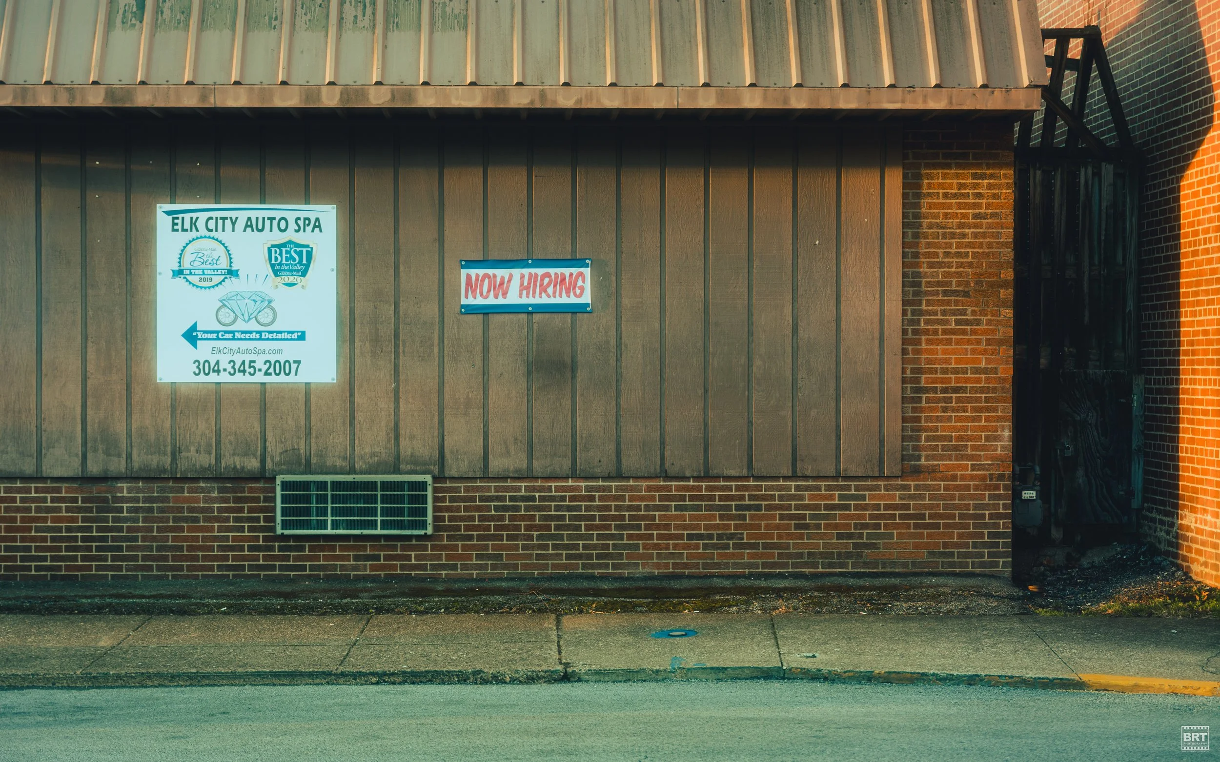 Sign on building advertising car spa, with a smaller sign indicating now hiring.