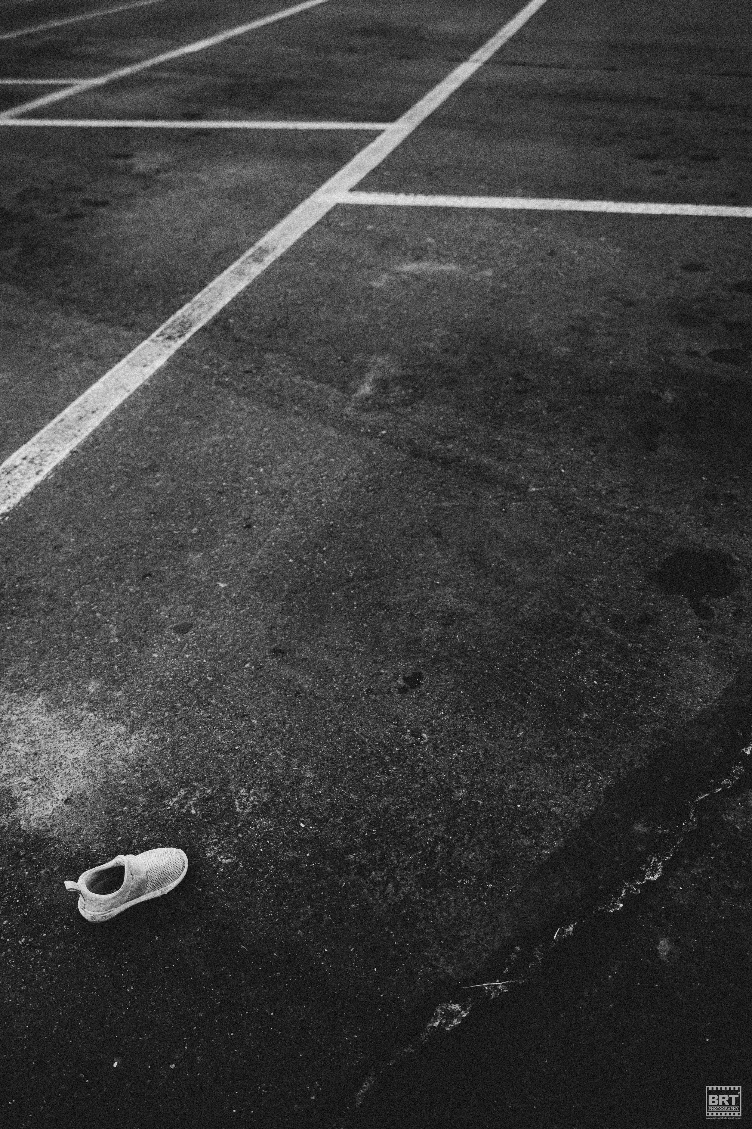 An empty parking lot at night with a single sneaker on the ground.