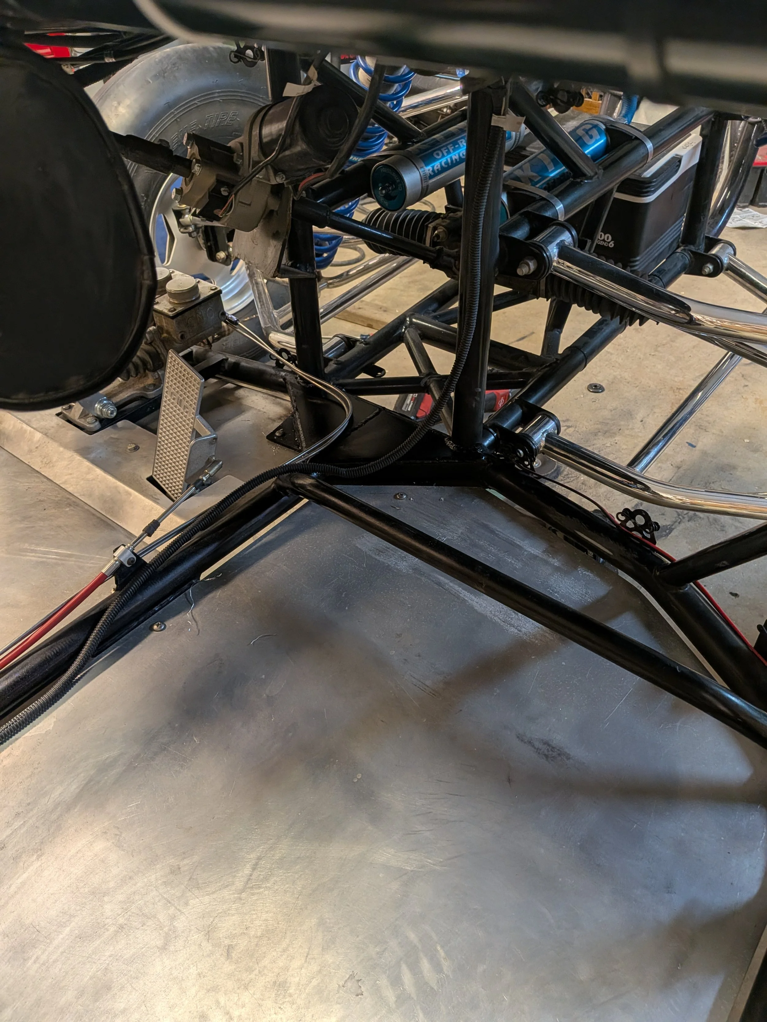 Close-up view of a racing car's chassis and mechanical components, including shock absorbers, wiring, and metal framework.