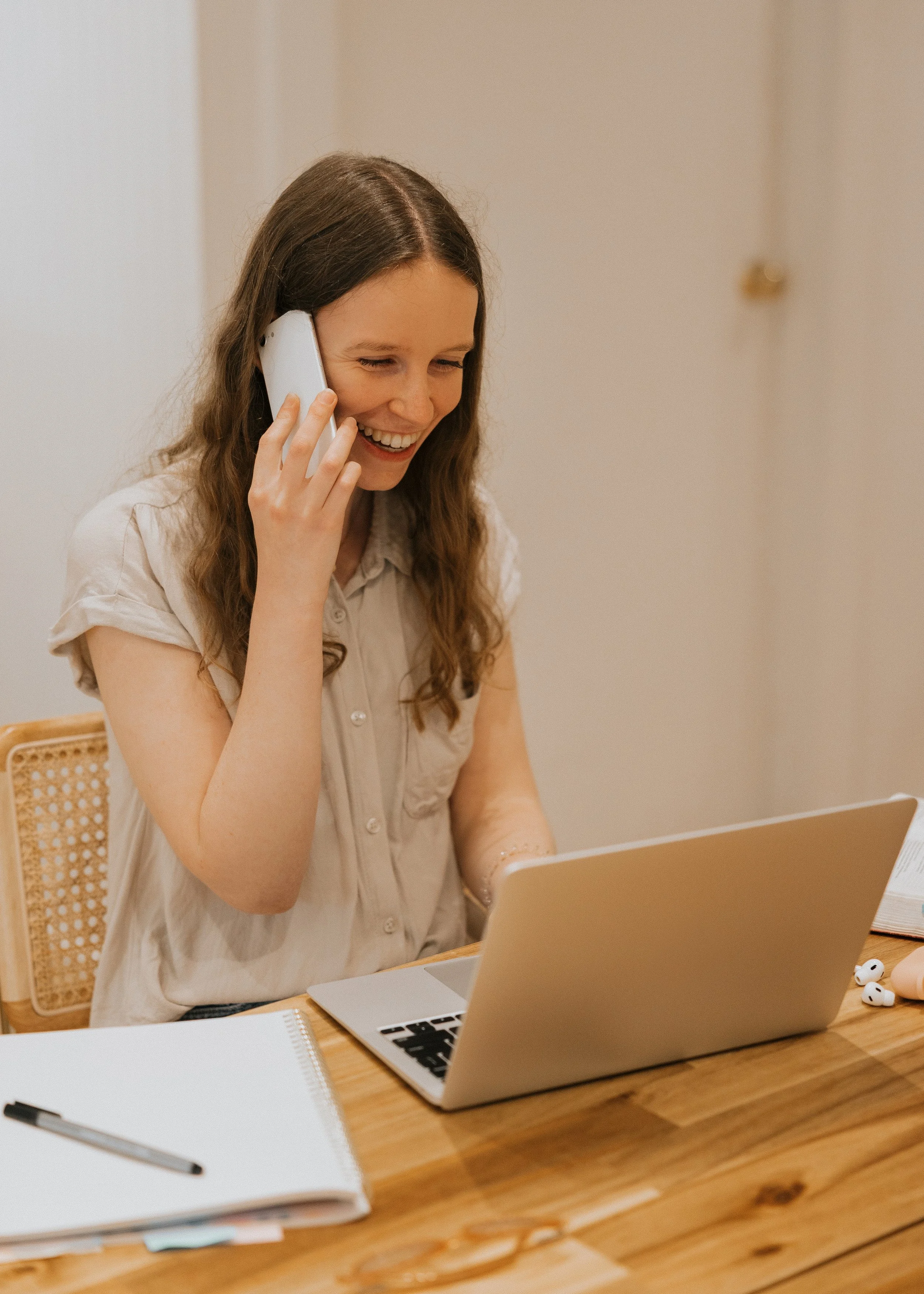 Woman smiling while on the phone with a client, looking at her computer
