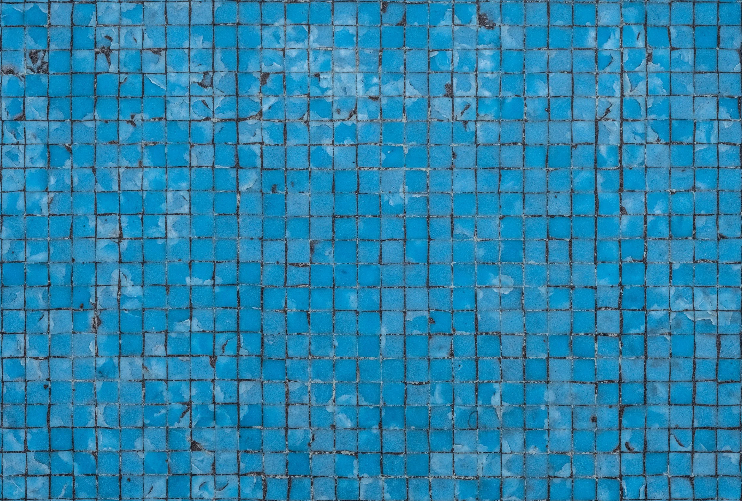 Close-up image of small blue square mosaic tiles, some of which are chipped or cracked.