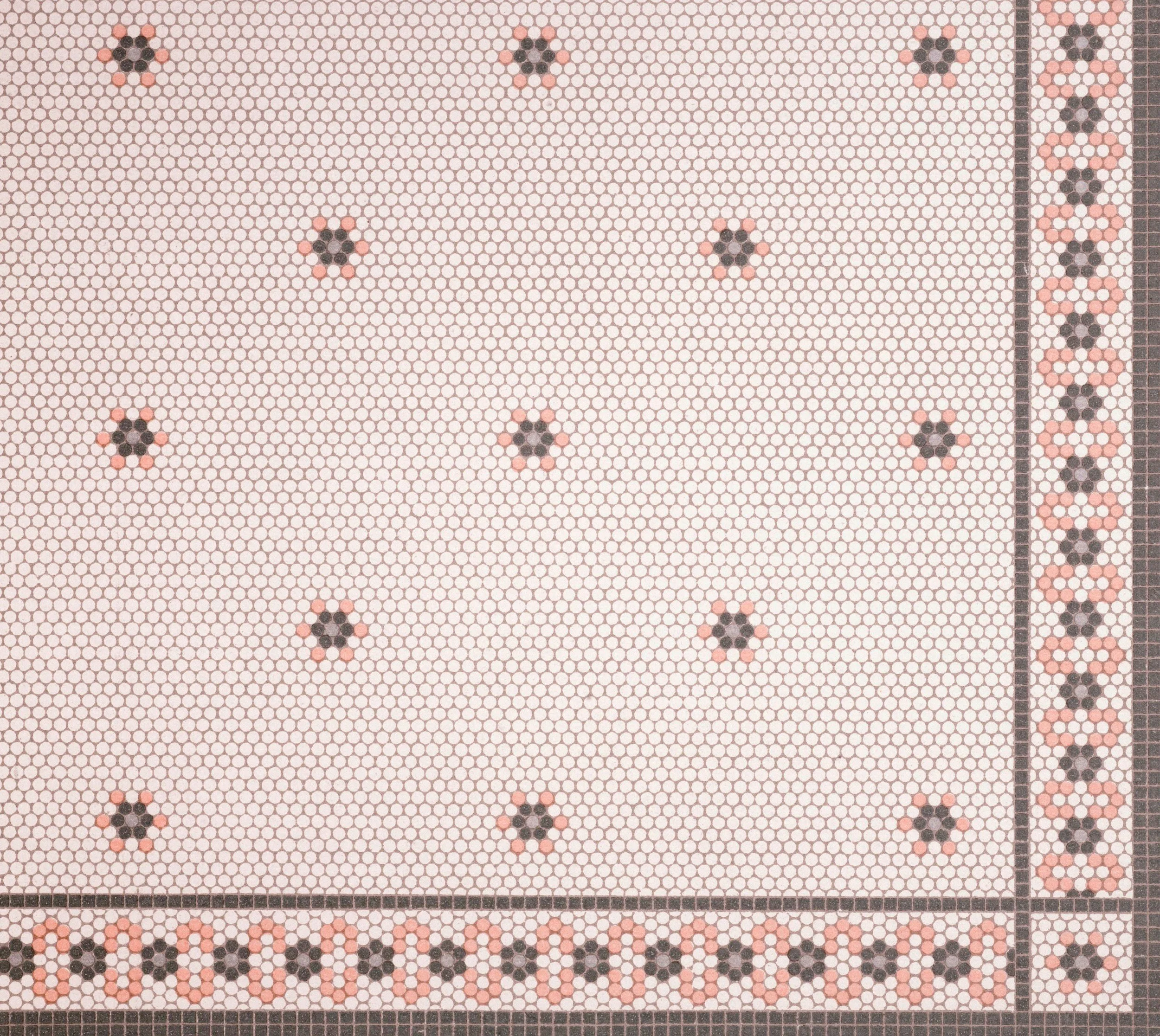 Mosaic tile floor with a pattern of small hexagonal tiles in pink, black, and white. The floor has a border with a circular floral motif, and fitted within it are larger black and pink flower-like patterns.