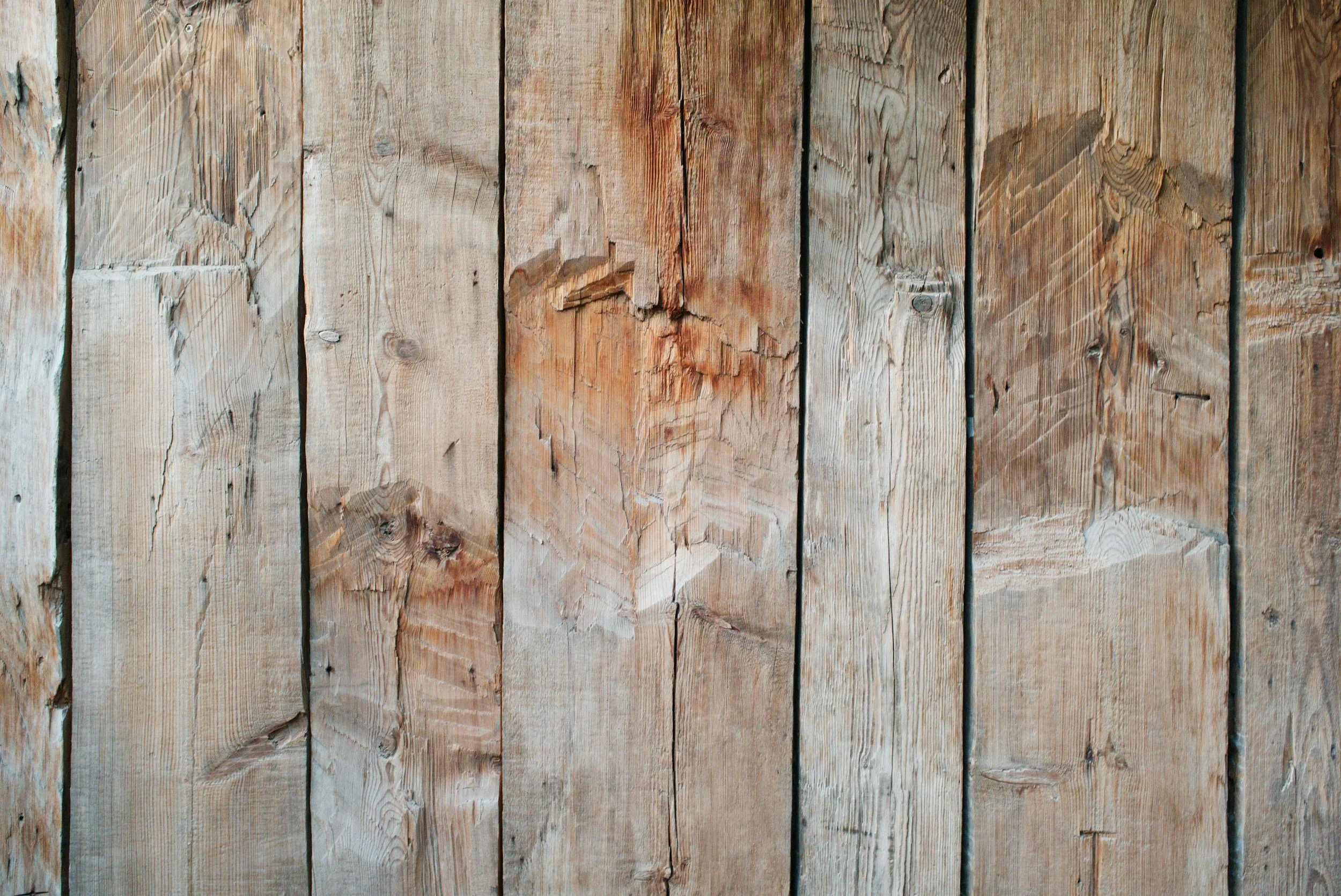 Close-up of weathered wooden planks arranged vertically, showing natural grain and some cracks.