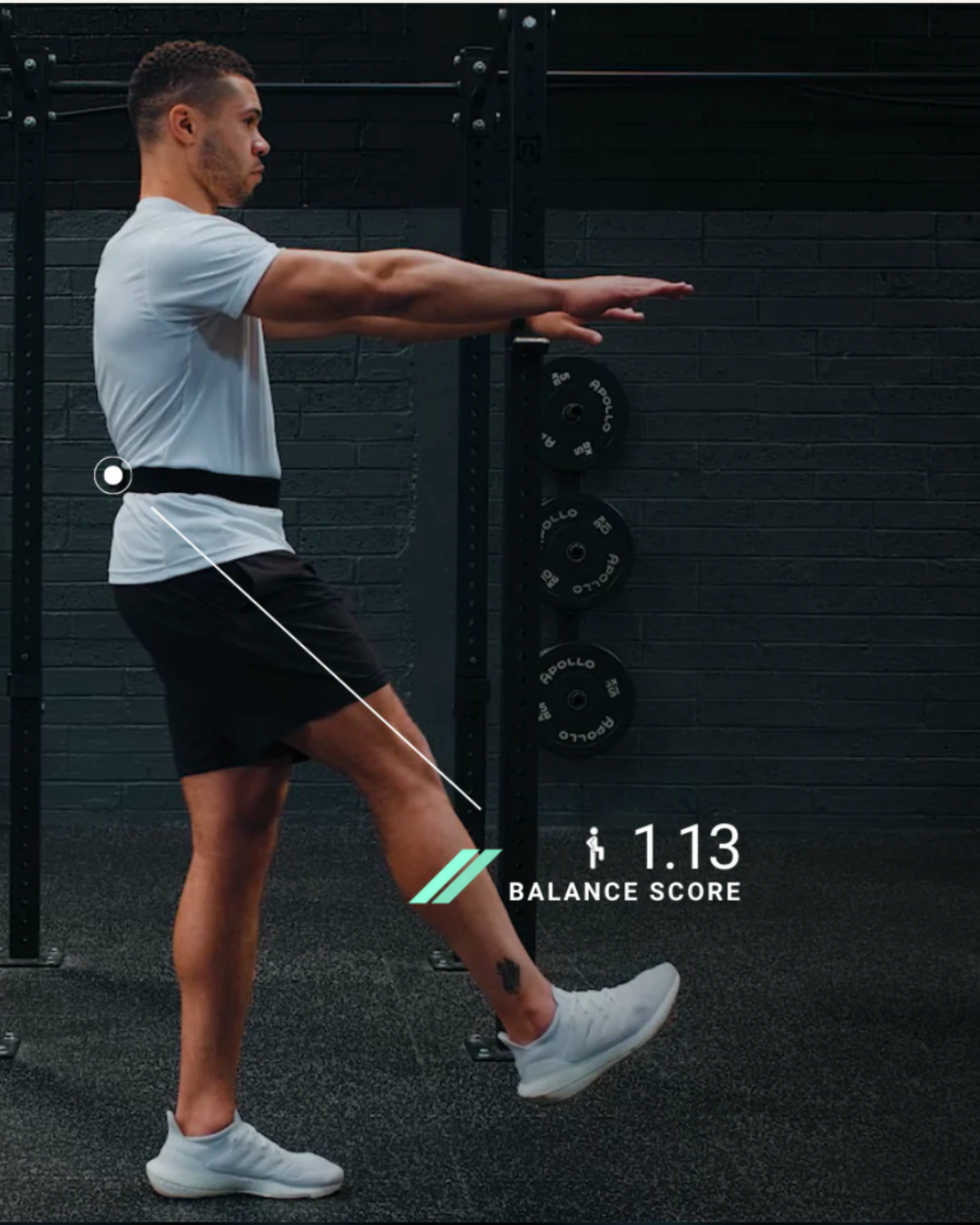 A man in gym attire performing a balance exercise with arms extended forward, standing on one leg. He is completing his fitness profiling session to determine mobility, flexibility, endurance, strength and power.