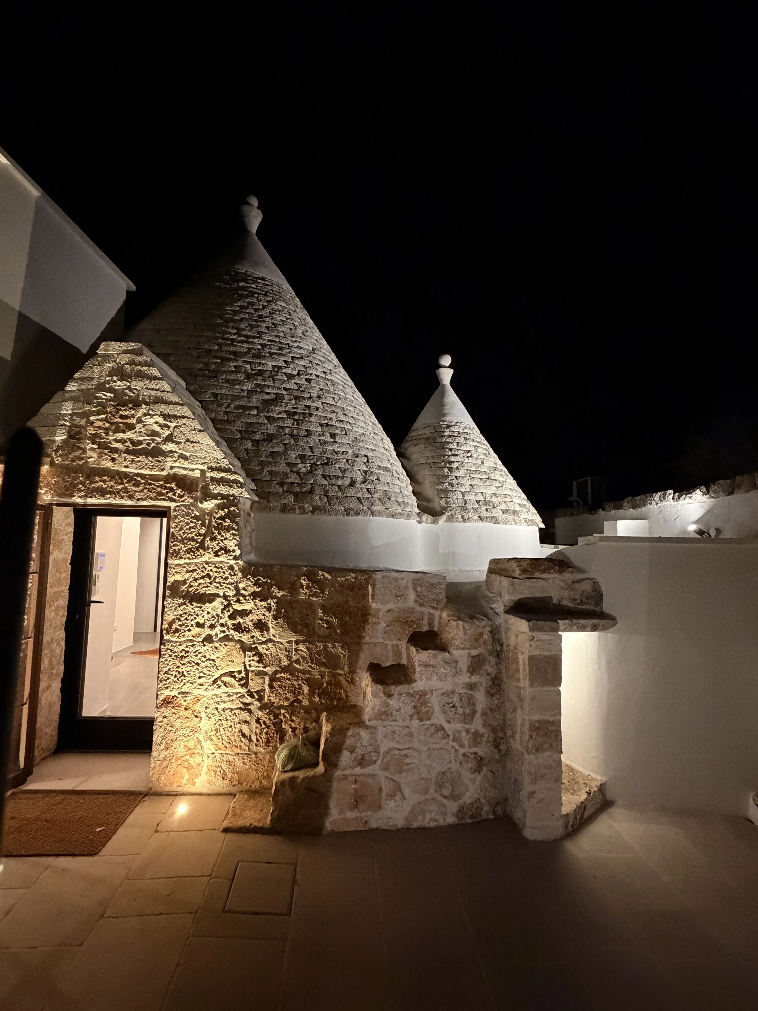 Stone trullo cones lit at night at Trullo Ostro