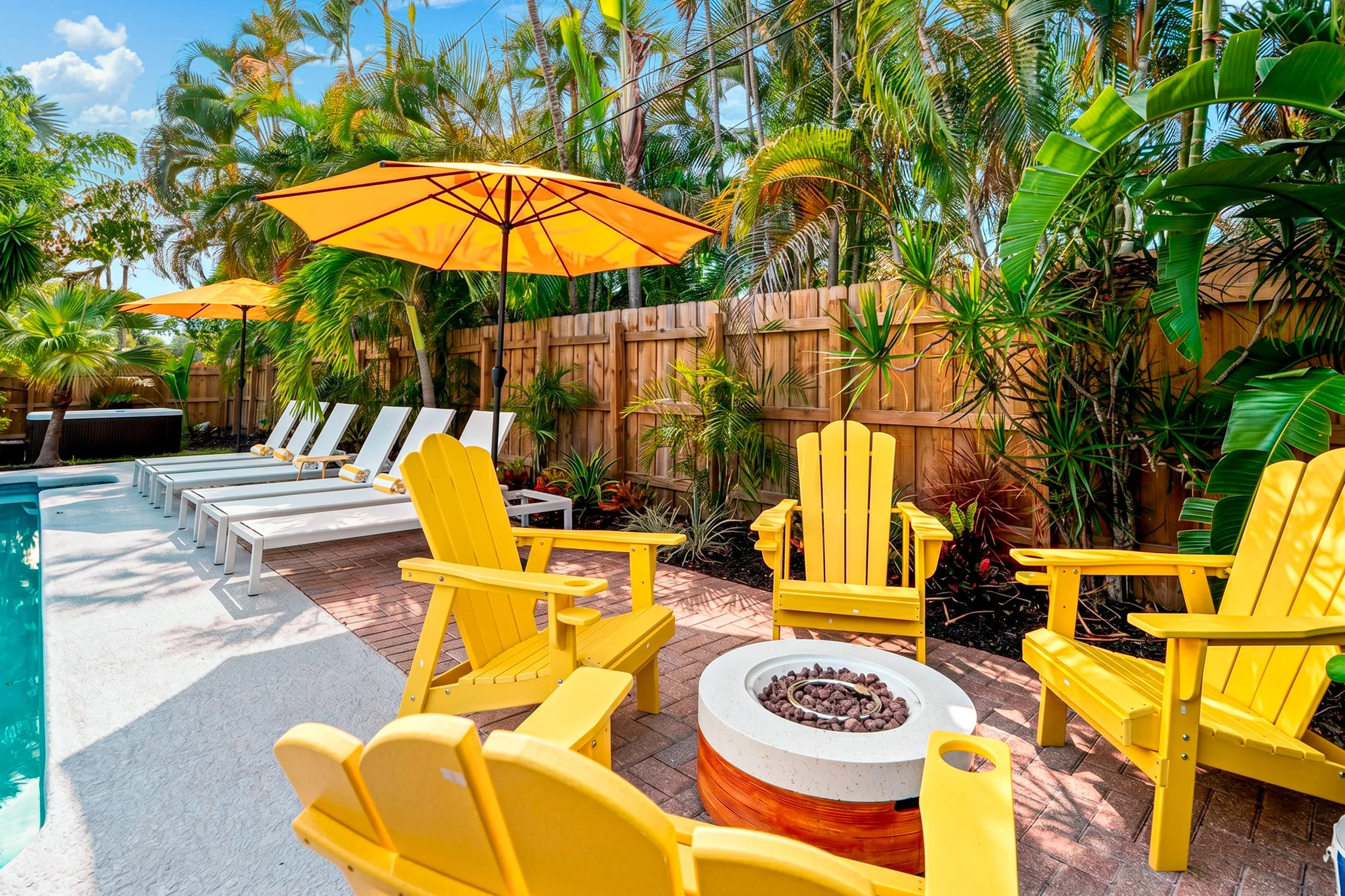 Yellow Adirondack chairs around the fire pit by the pool at Mangrove Manor